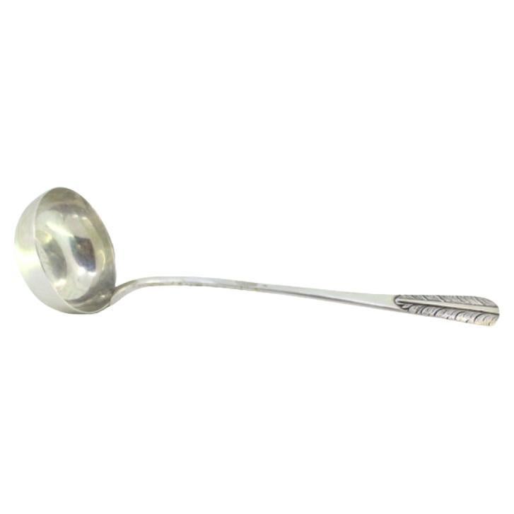 Smooth silver soup ladle with reliefs on the handle