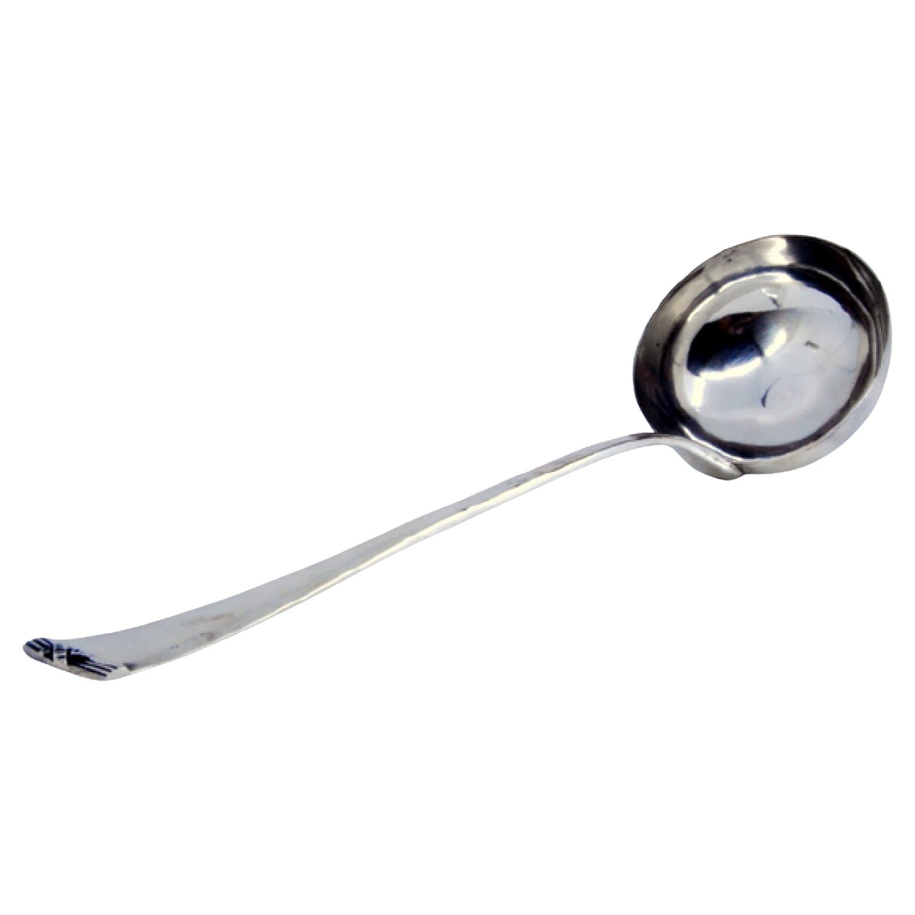 Smooth silver soup ladle with small relief on the end of the handle