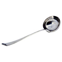 Smooth silver soup ladle with small relief on the end of the handle