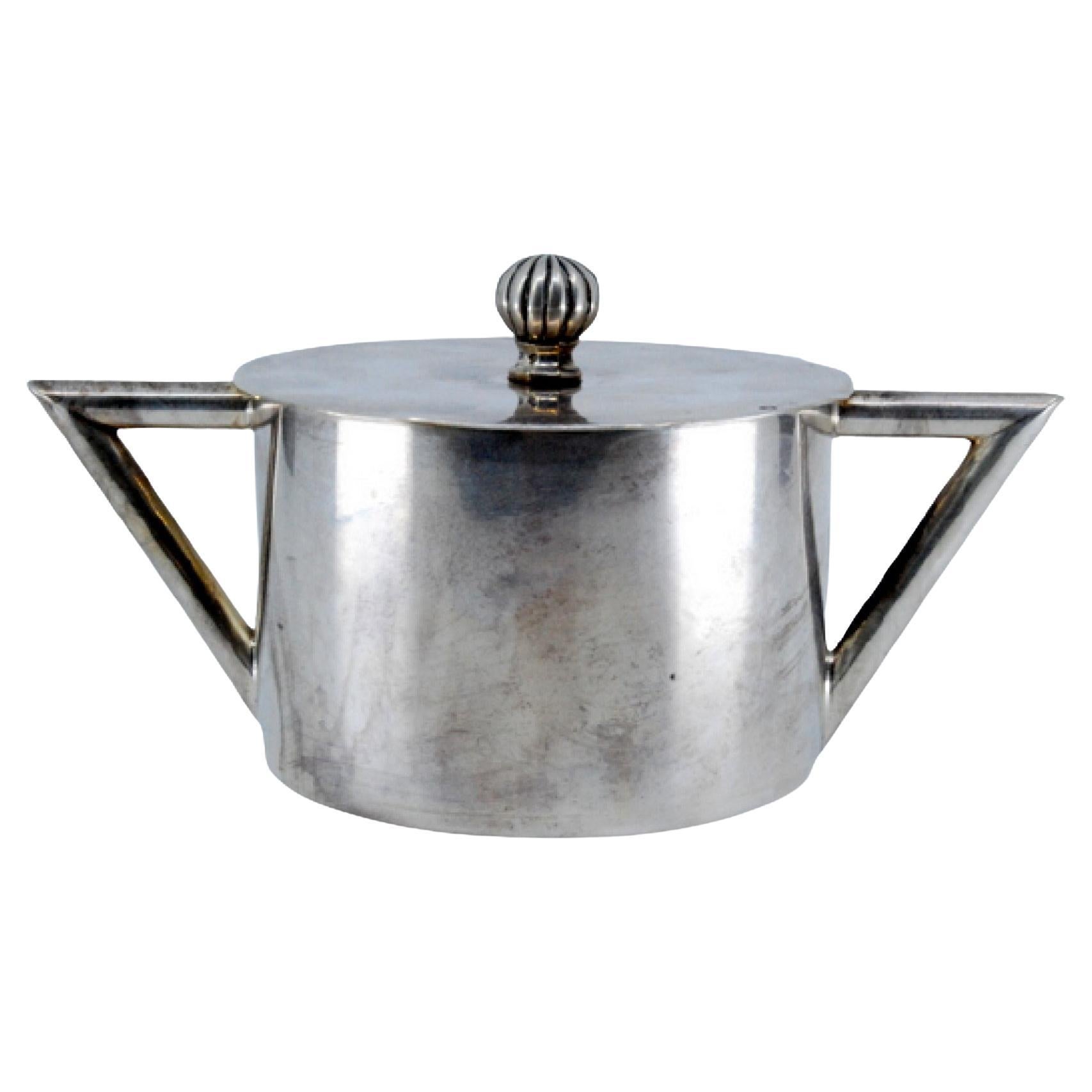 Sucrier en argent lisse avec un bouton en caoutchouc sur le couvercle et des poignées géométriques.