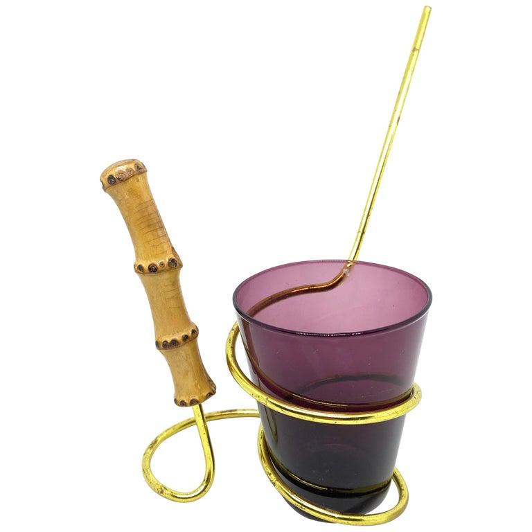 This lovely piece is typical, 1950s. The glass is for salt sticks or nuts and the golden metal stand is for pretzels.
The handle is made of bamboo. The glass is purple colored and the metal holder is in gold with some patina.
The set is in very