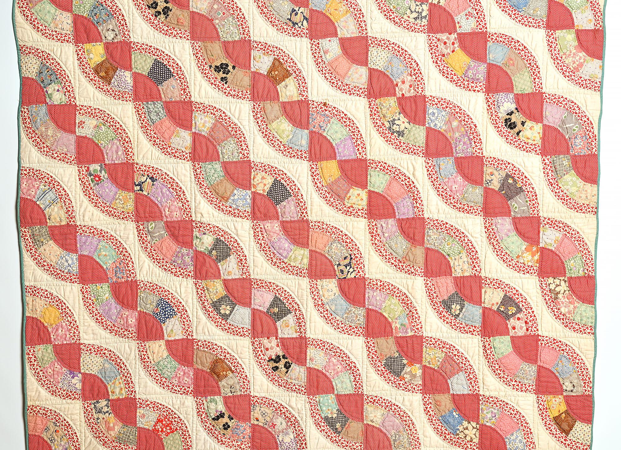 This cheerful Snail's Trail quilt done in an assortment of 1930's printed fabrics. Tiny white polka dots on red make the centers stand out while outlined in a print with three leaf clovers. This is a pattern not often seen. The size of the quilt as