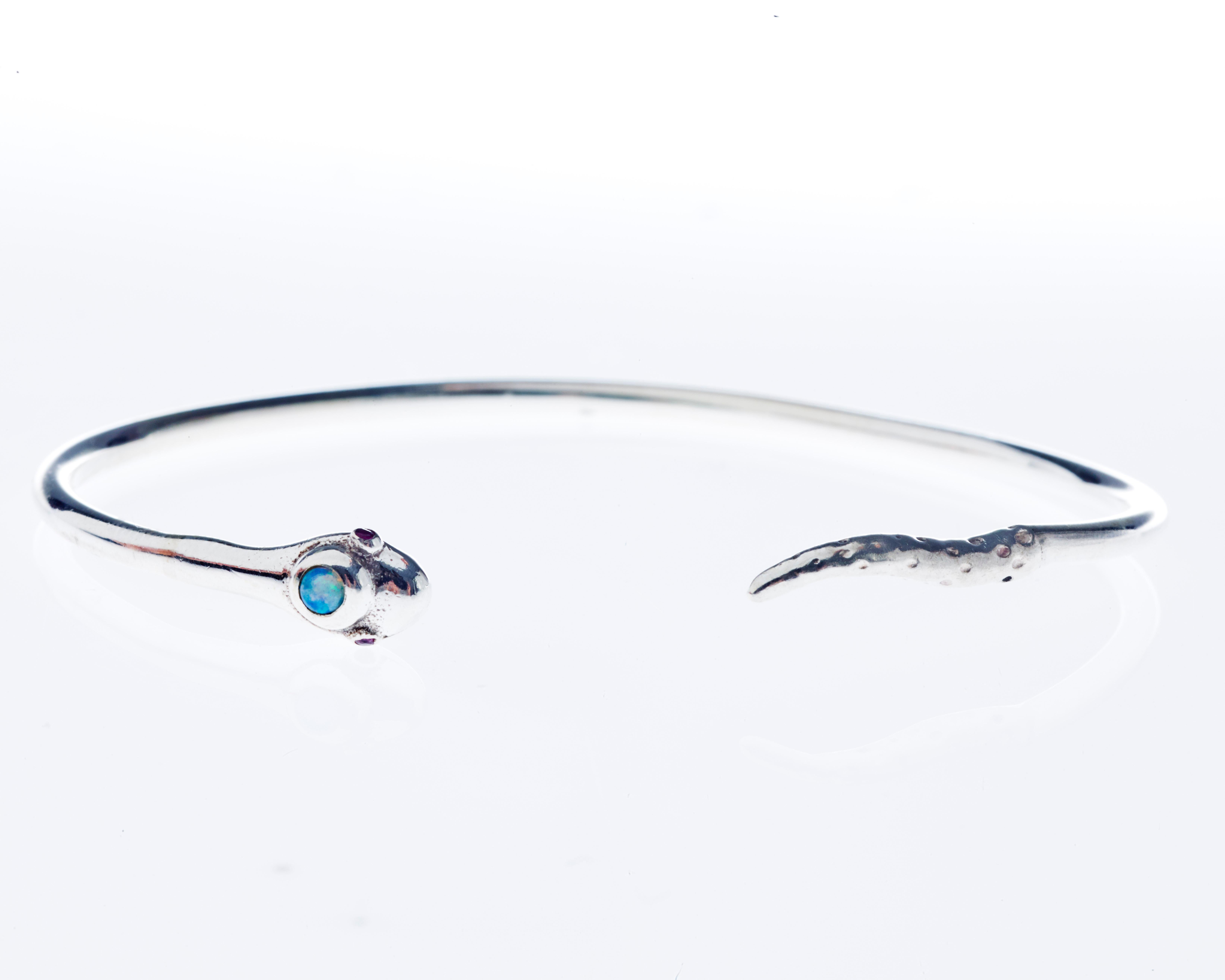 Bracciale bangle a serpente in argento, ornato da opale e rubino, progettato in stile vittoriano. Realizzato su ordinazione. Completamento 3-4 settimane.

Il serpente è da sempre simbolo di trasformazione, rinnovamento e protezione. In gioielleria