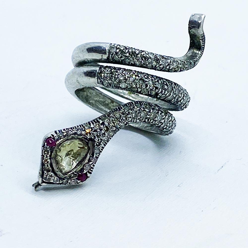 Snake Ring Silver-Diamond set in an Egyptian style motif 
The ring is a triple, Size 6 shank expanding 40 mm from tip of head to the tail. The 150 diamonds are encrusted in prongs measuring 1.50-1.60 mm each. 
The larger cut diamond measures 6 x 4