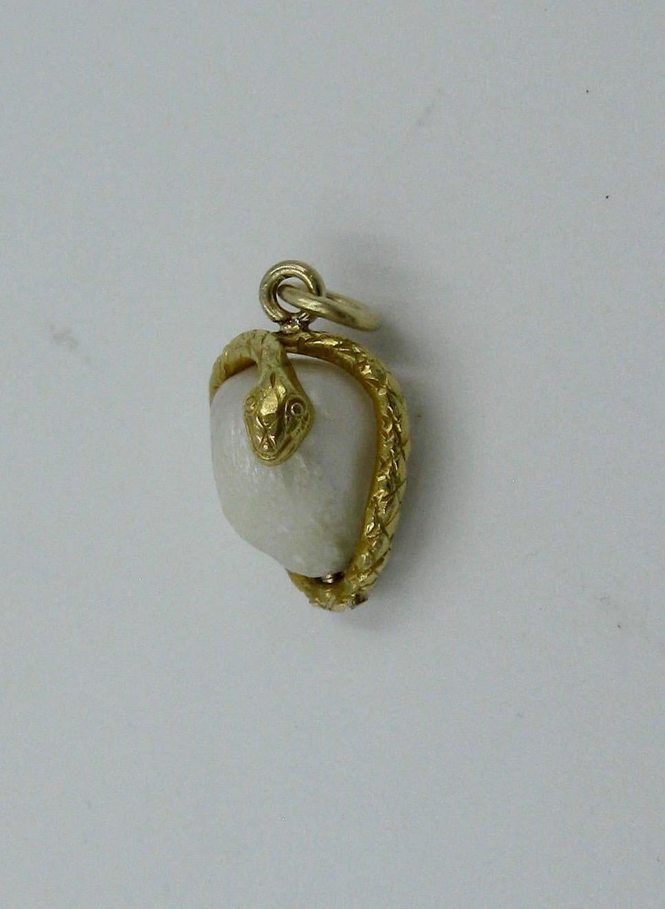 A rare antique Victorian Snake Pendant depicting a snake or serpent wrapped around an egg.  The snake in 14 Karat gold with wonderful engraved details throughout the head, and extending through the tail.  The egg a gorgeous Baroque Pearl. The snake