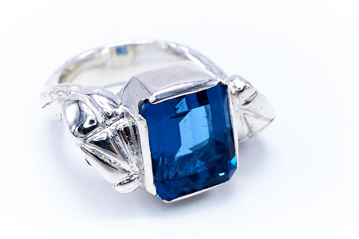 Blue Topaz and Emerald Snake Ring in Sterling Silver – “Parfois” Statement Ring by J DAUPHIN

This handcrafted statement serpent ring from the “Parfois” collection by J DAUPHIN is cast in sterling silver, set with a radiant blue topaz baguette, two