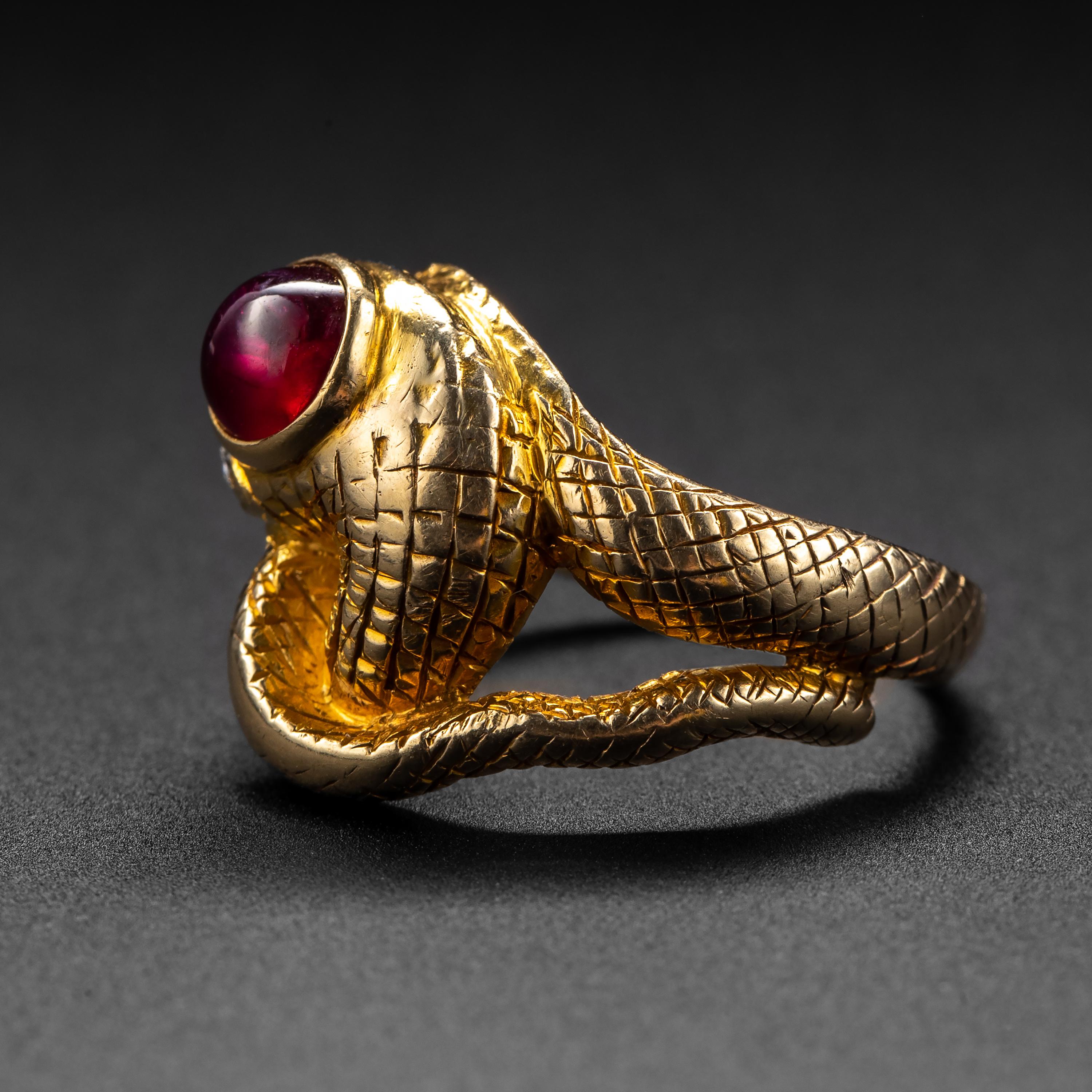 A rare and wonderful Art Nouveau-era snake ring hand-crafted in 14K gold and set with a superb bright red certified unheated Burmese ruby weighing 1.5 carats. A pair of tiny old sparkling white diamonds are the eyes of this twisty, grinning