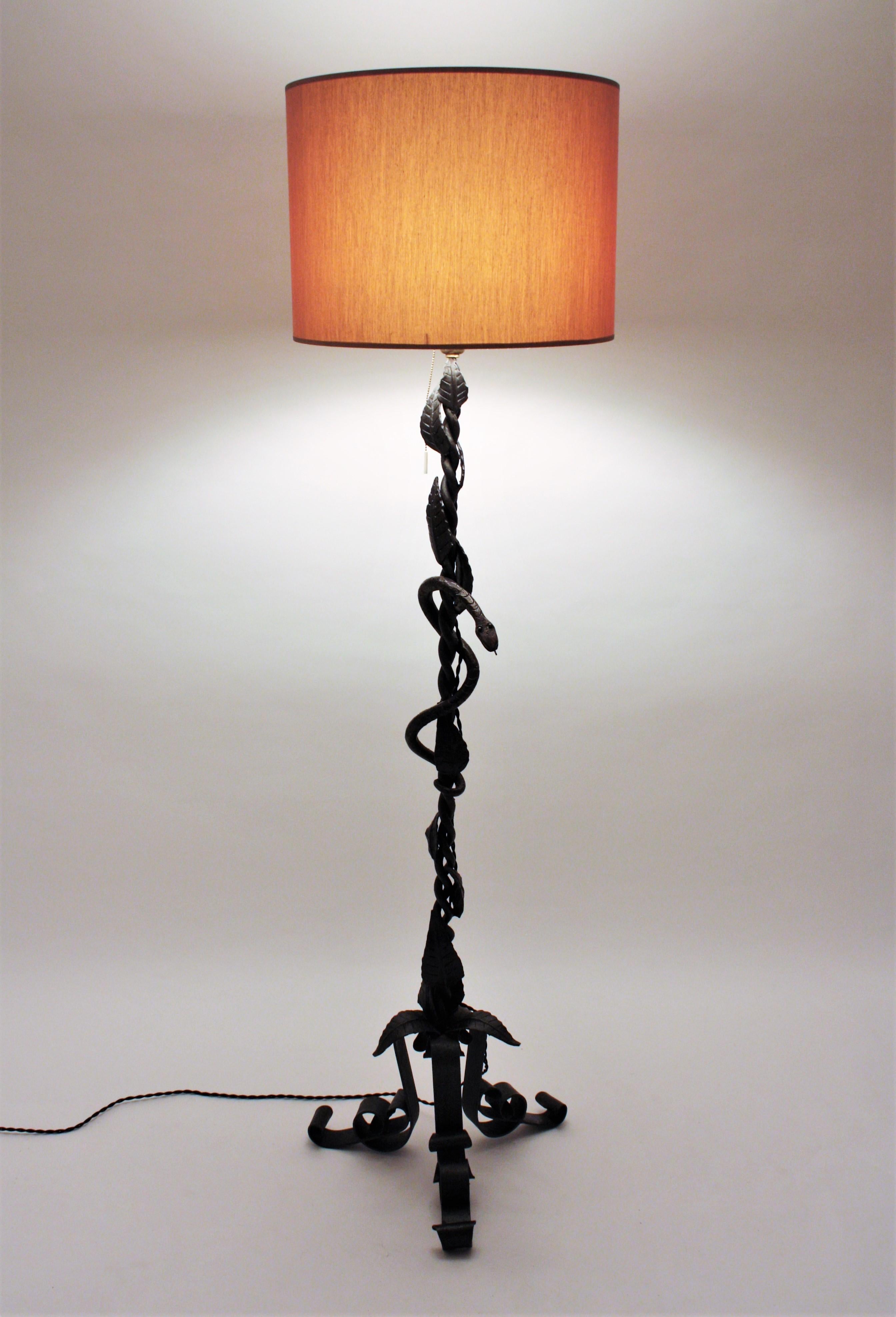 Hand forged iron floor lamp with snake and leaves decoration standing on a tripod base, Italy, 1930s.
This floor lamp has reminicences of Umberto Bellotto designs and is all made of handwrought iron. Its most striking feature is a coiled snake