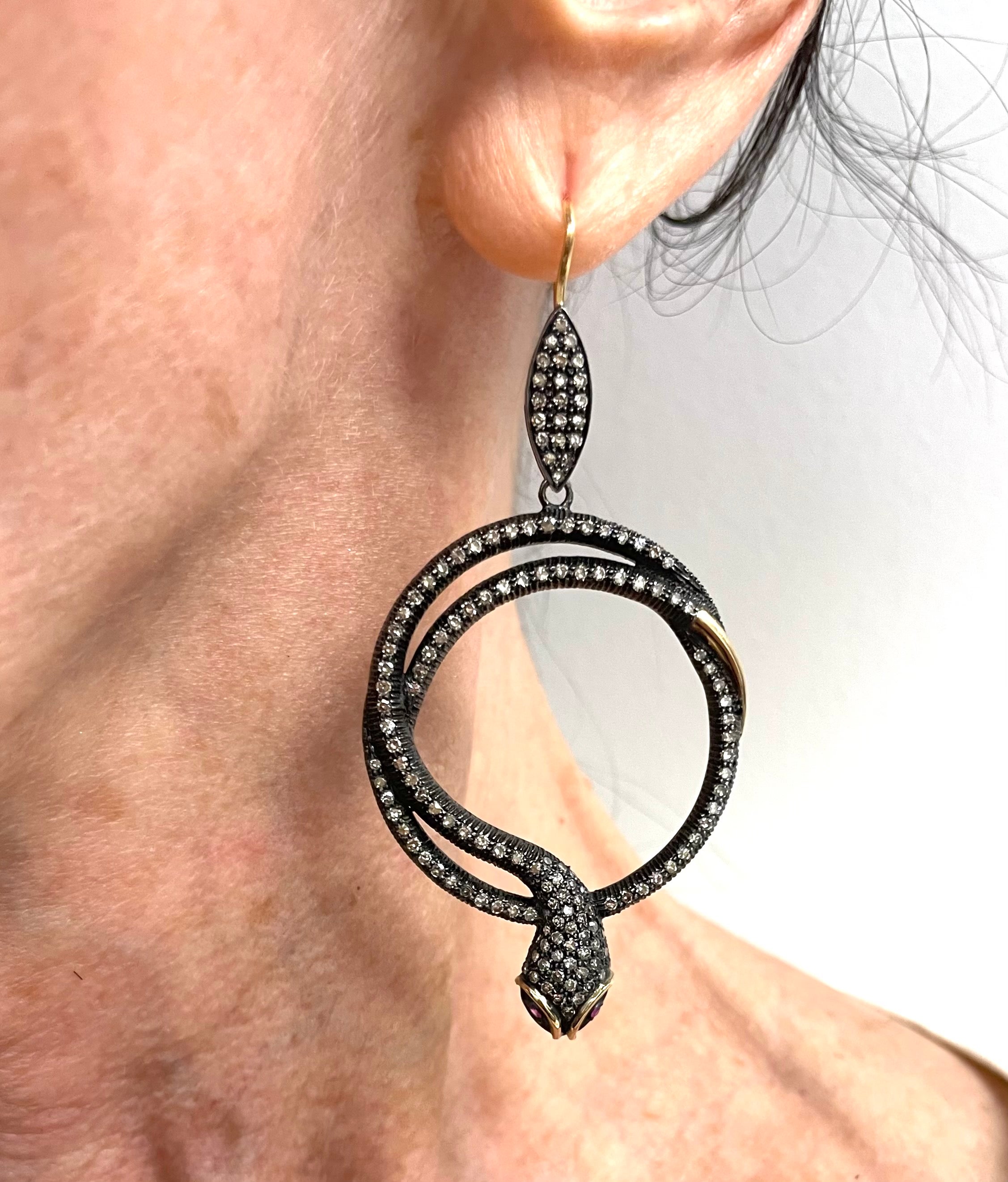 Description
Striking, exquisite and edgy, yet feminine Serpents accented with Ruby eyes and embellished with pave diamonds set in black rhodium sterling silver. Yellow gold details on the head and tail create a dramatic contrast making these