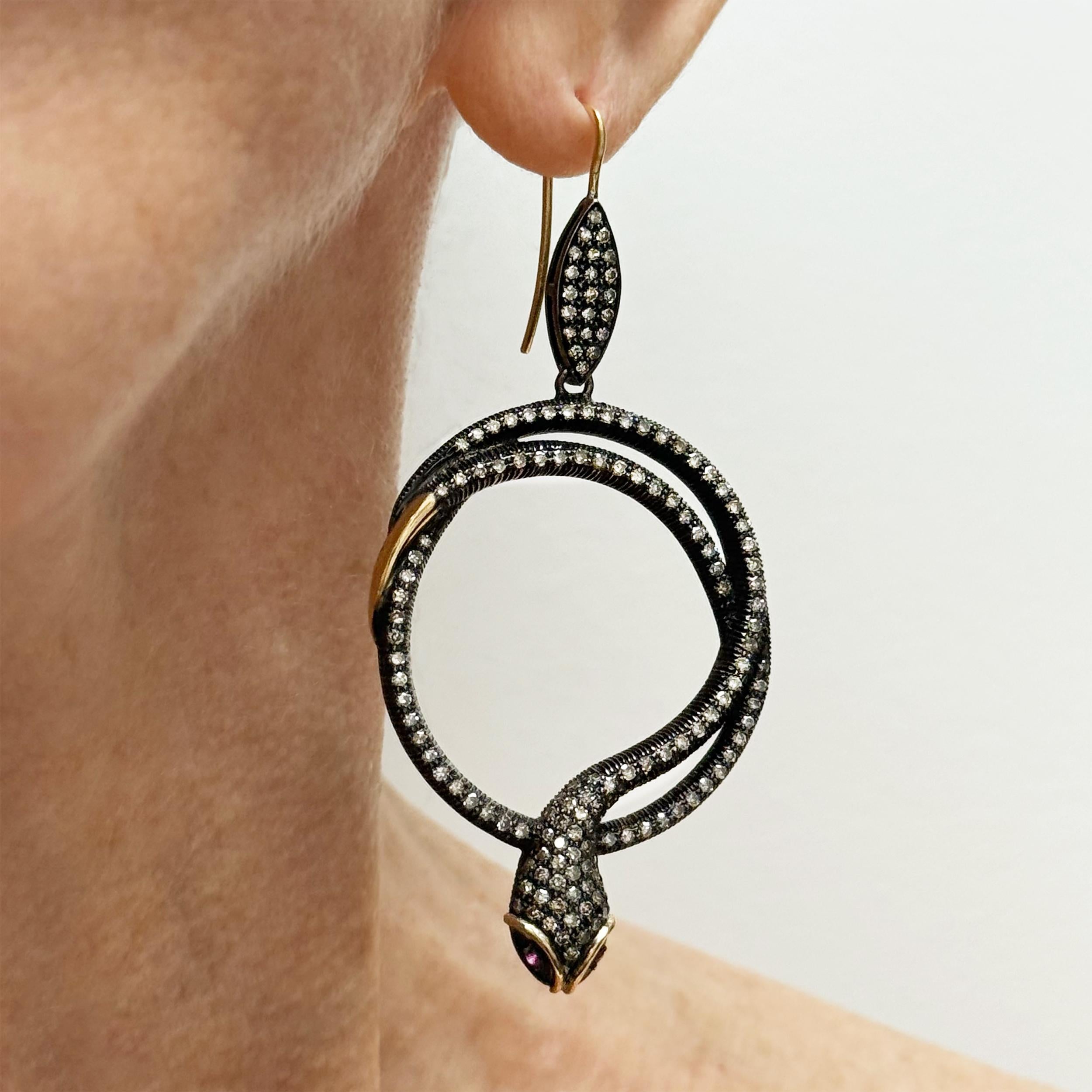 Description
Des serpents saisissants, exquis et audacieux, mais féminins, accentués par des yeux en rubis et embellis par des diamants pavés en argent sterling rhodié noir. Les détails en or jaune sur la tête et la queue créent un contraste