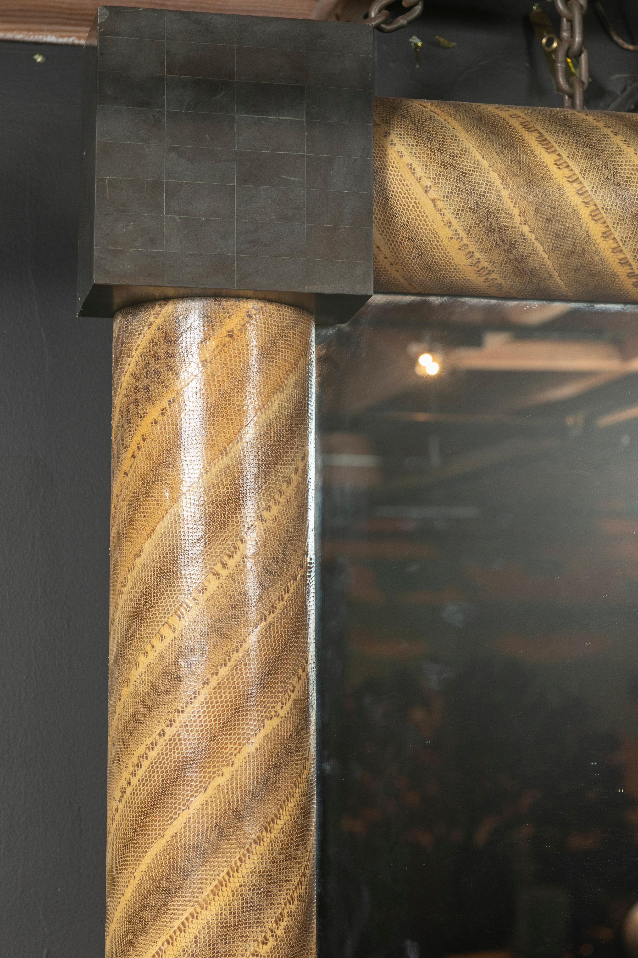 This Mid-Century Modern rectangular mirror is spiral wrapped in snakeskin embossed leather finished with tessellated stone corners. Made in the design style of Karl Springer, the mirror can be hung either horizontally(pictured) or vertically for