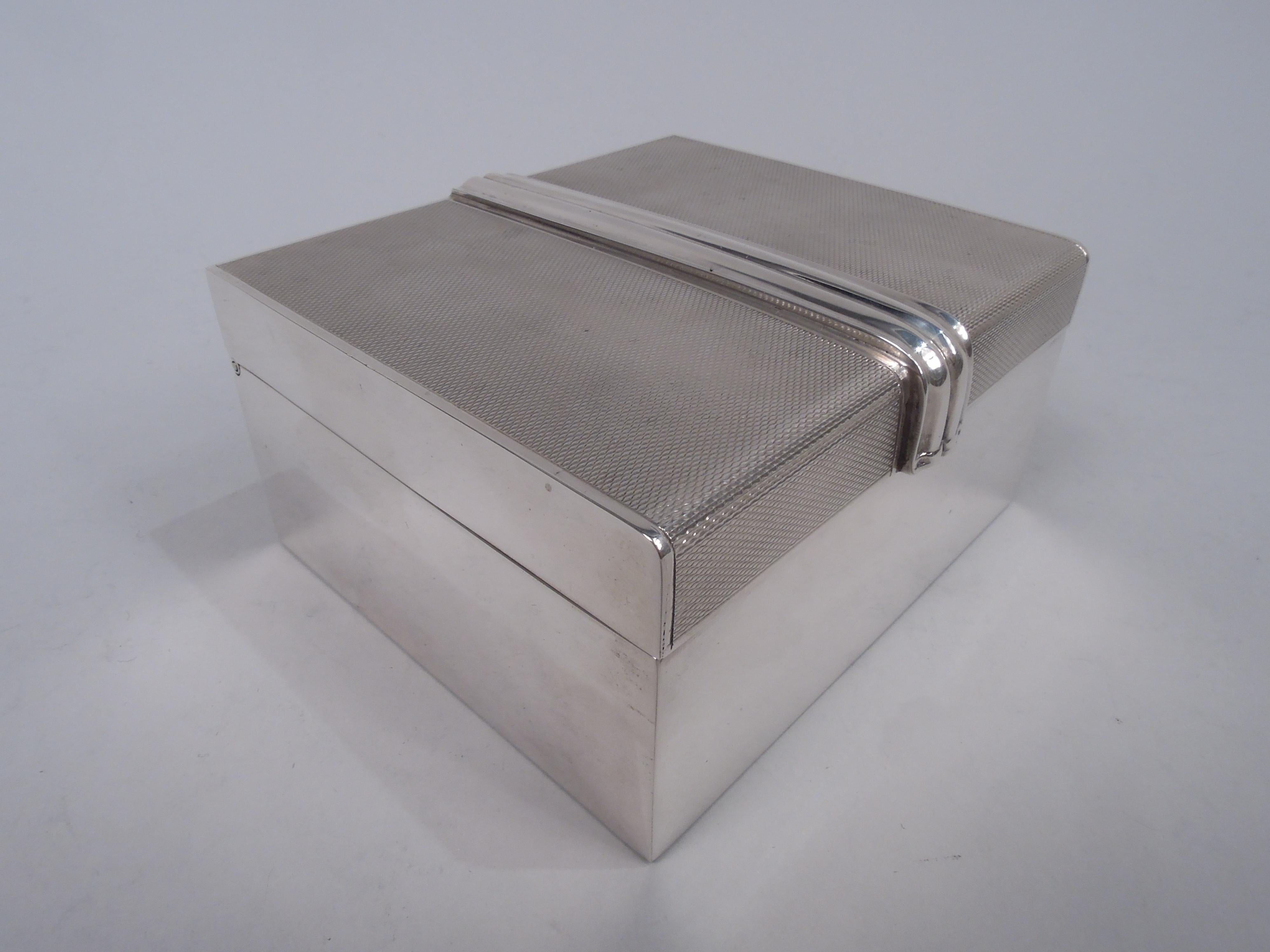 Snazzy Art Deco sterling silver box. Made by William Suckling in Birmingham in 1951. Rectangular with straight and plain sides. Cover hinged with plain sides and back. Top and front have allover engine-turned ground and are bisected by applied