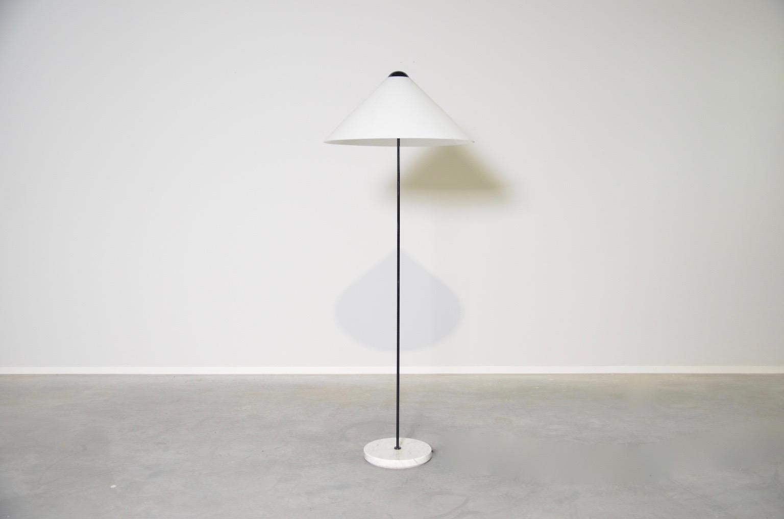 Floor lamp designed by Vico Magistretti for Italian firm Oluce. The white semi translucent shade is resting on a very thin black stem ending in a marble round base. When lit, the shade almost seems to hover. The lamps uses two 60W bulbs (E27).