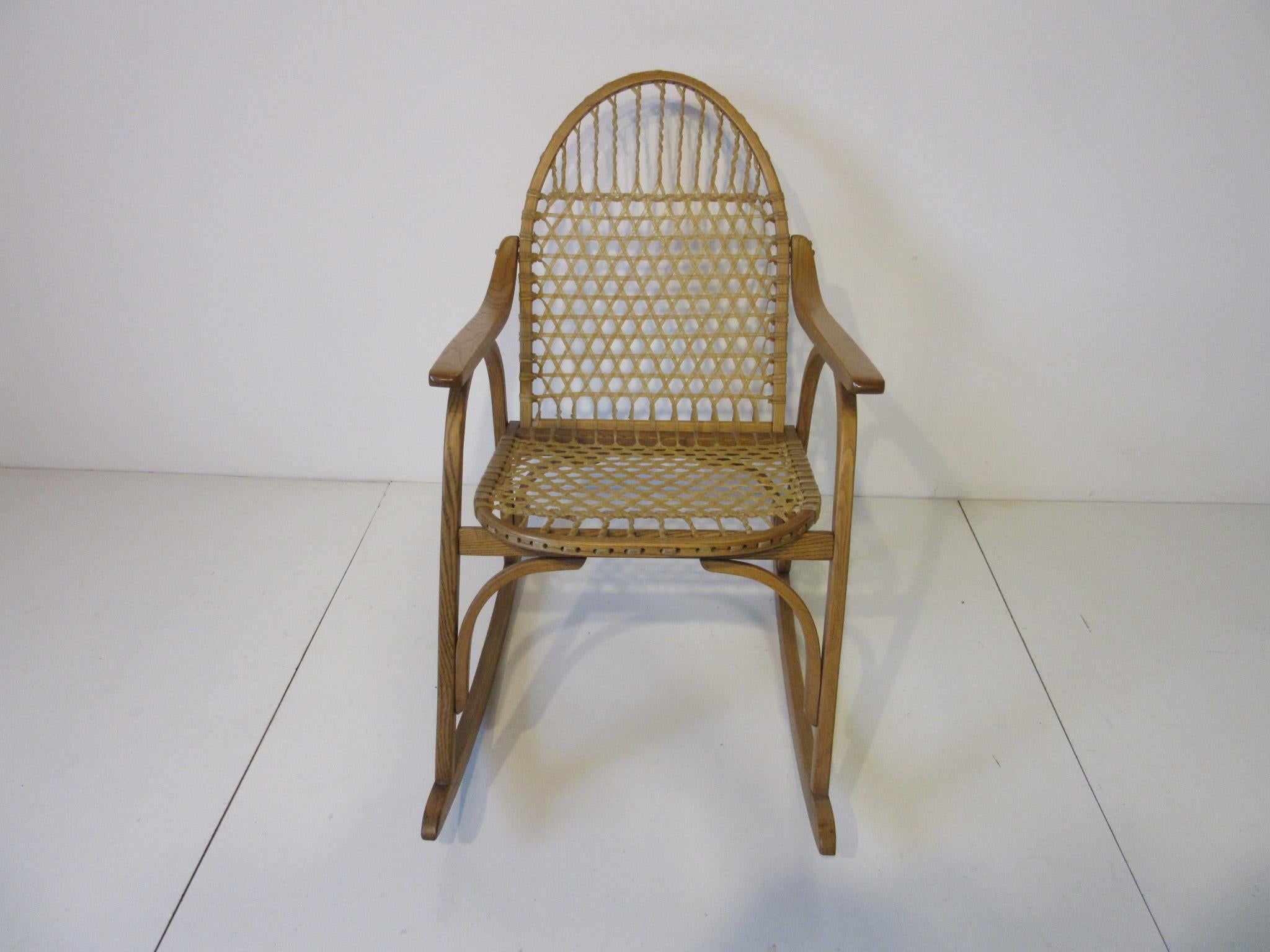 A white ash bentwood framed rocking chair with water buffalo gut strung seat bottom and back in the manner of a snow shoe. This handcrafted chair was made by Vermont Tubbs which has been producing them since 1840. A true classic for that cabin,