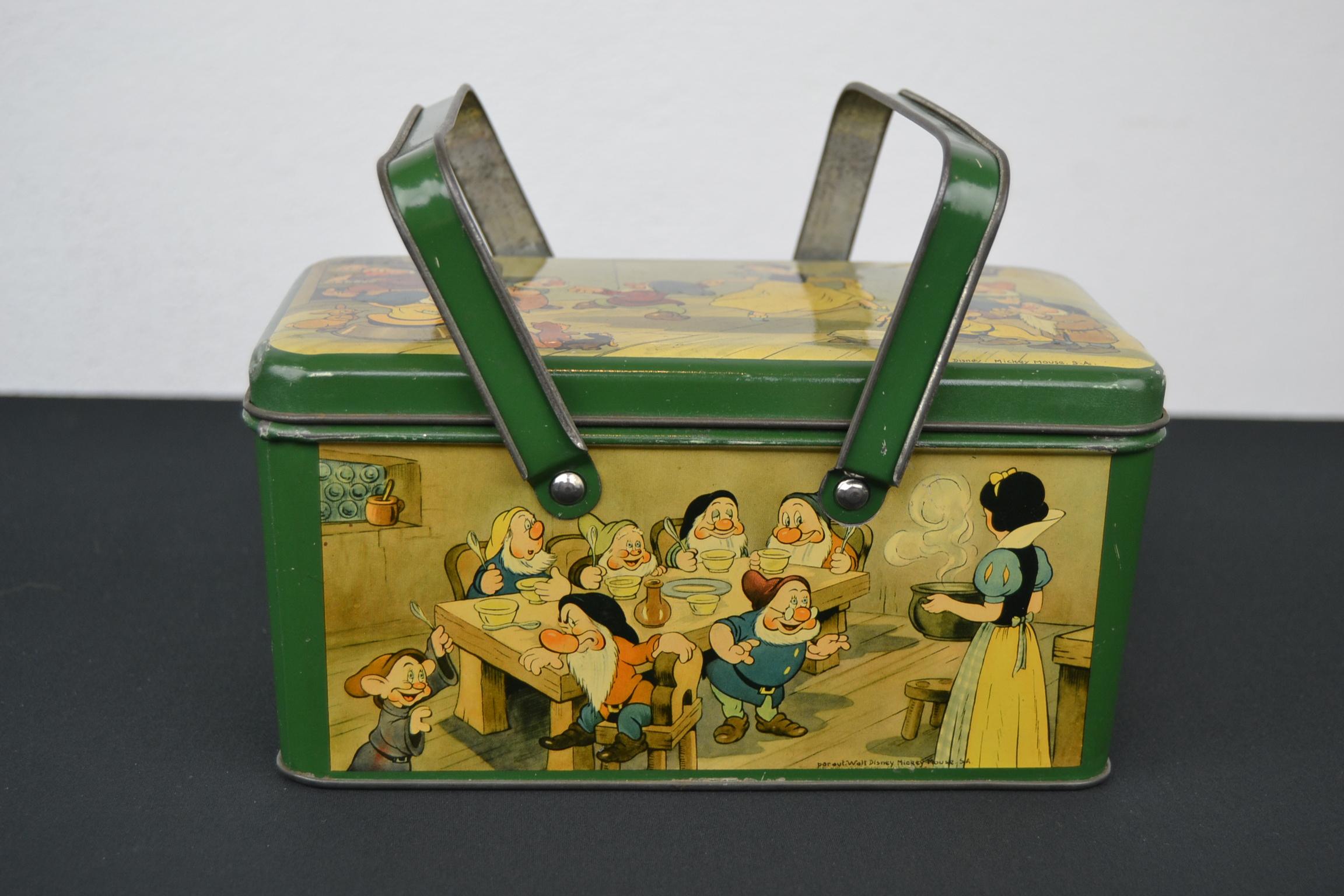Late 1930s lithographic tin with handle showing snow white and the seven dwarfs all around. Each side has a different scene, and on each side it's marked: par auteur Walt Disney, Mickey Mouse SA or under licence of. This Belgian Tin with Snow White