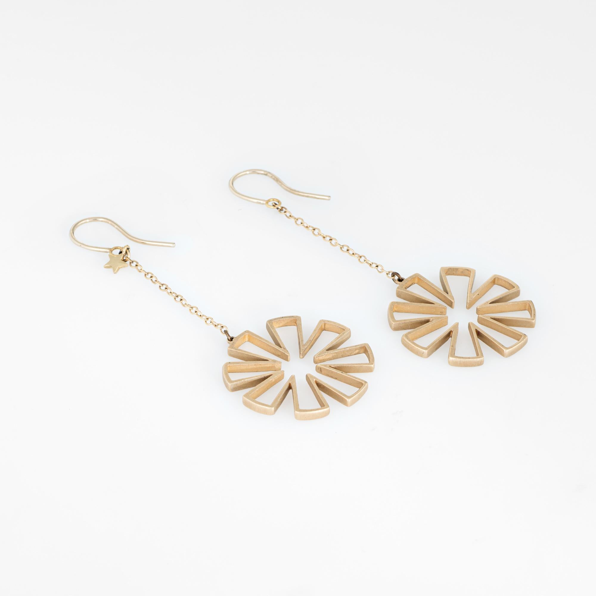 Elegant pair of estate snowflake drop earrings crafted in 14k yellow gold. 

The long 2 1/2 inch earrings feature a round star or snowflake style design. A small star is attached to one of the earrings (upper). The stylish earrings are ideal for day