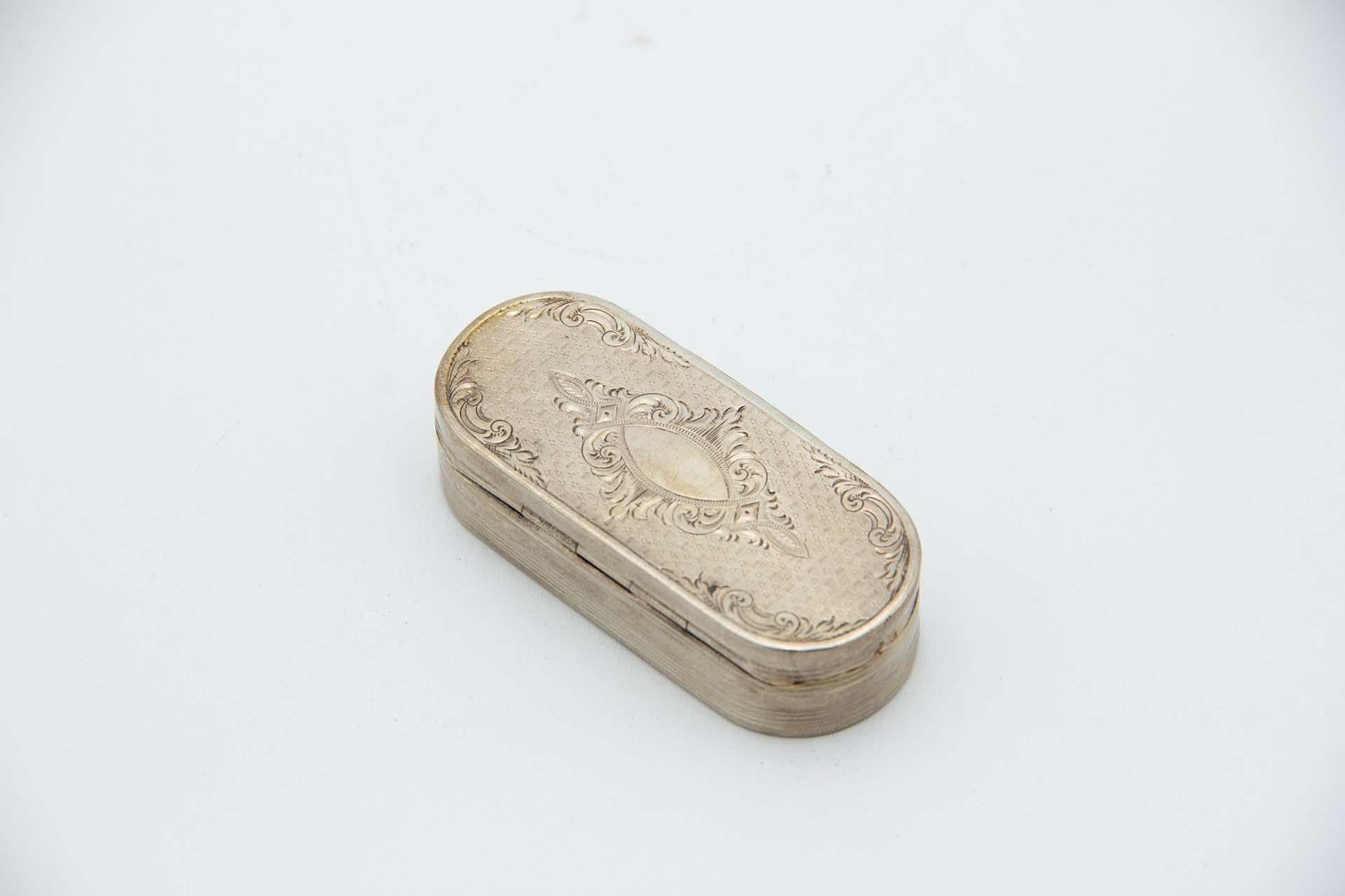 Description : Tabatière en argent guilloché et gravures entourant une carte monogramme, entourant des frises et de forme elliptique. Métal : Argent. Origine : Portugais. Marque : boar II Titre. Poids : 57,05 grammes. Dimensions : 7,3 cm x 1,7 cm :