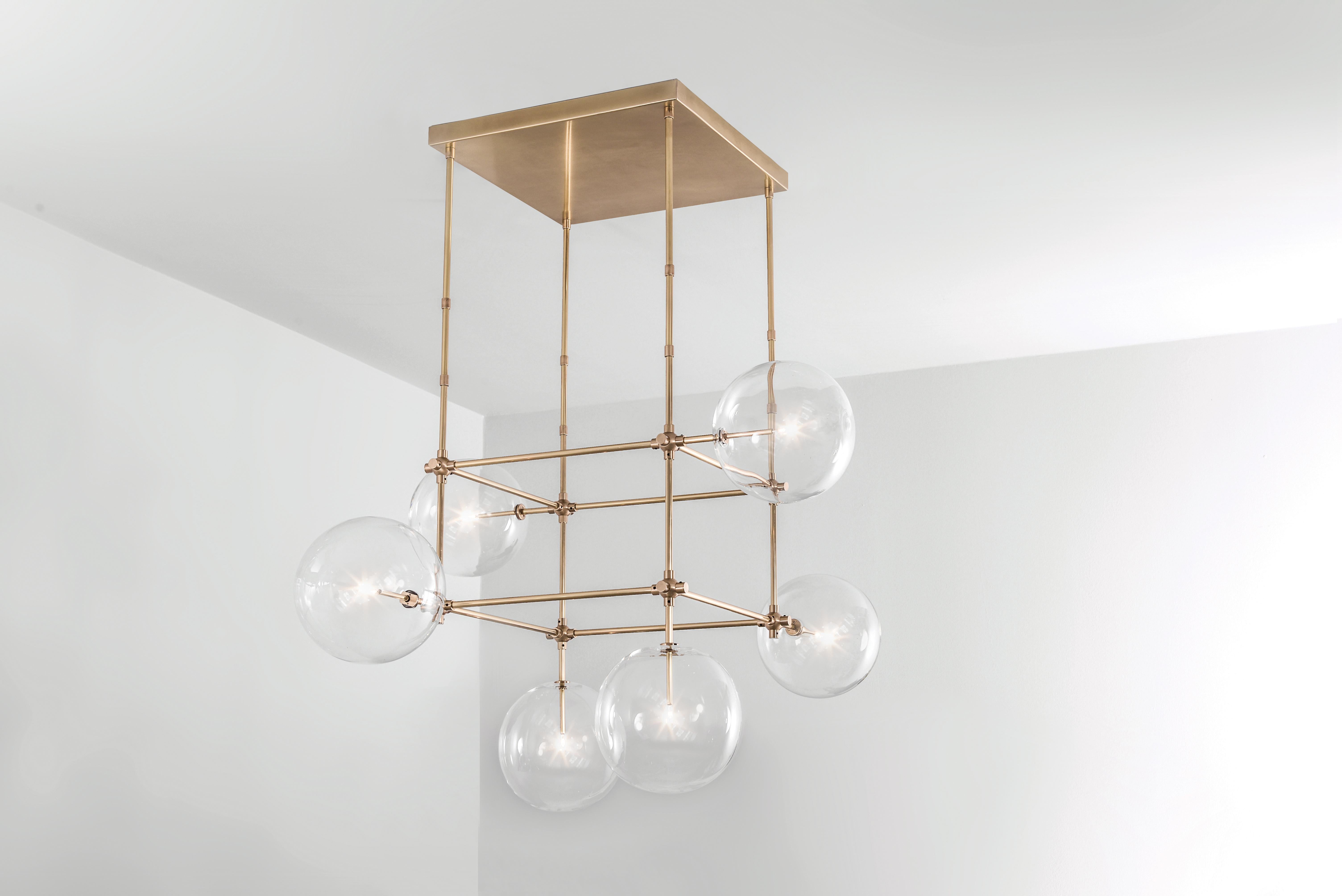 Brass 6 arm sculptural chandelier by Schwung
Dimensions: D 117.4 x W 117.4 x H 173.1 cm
Materials: Solid brass, hand-blown glass globes
Finish: natural brass.
Also available in finishes: black gunmetal or polished nickel.
All our lamps can be