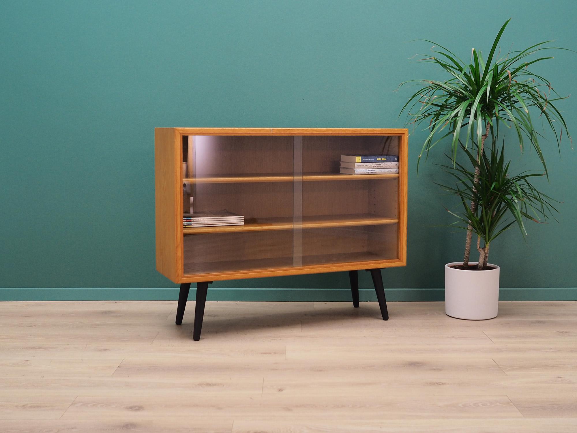Superb bookcase form the 1960s-1970s. Danish design, Minimalist form. Furniture is covered with ash veneer, legs are made of solid ashwood. Manufactured in Søborg Møbler manufactory. Bookcase has two adjustable shelves located behind a glass sliding