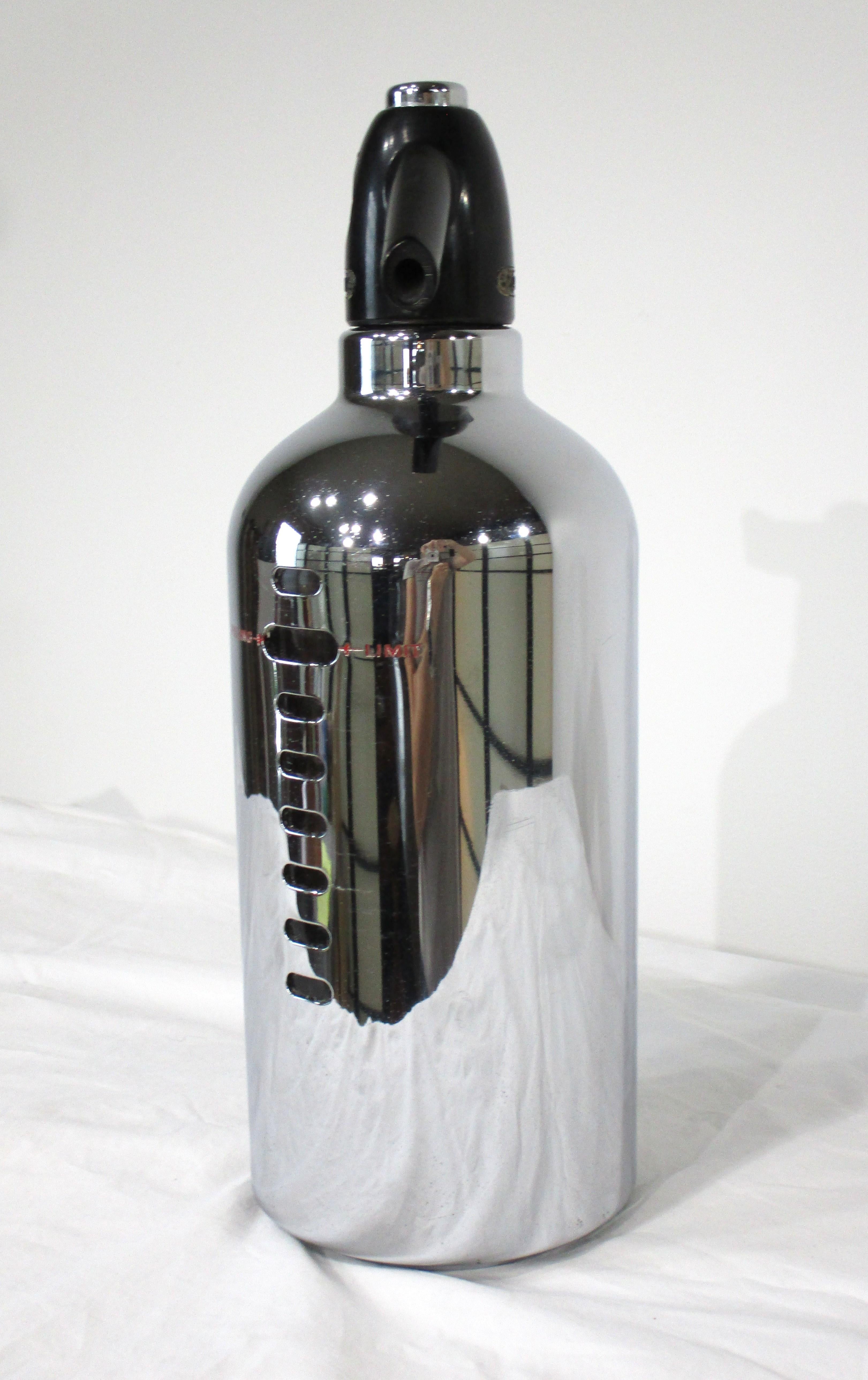 Eine stromlinienförmige, verchromte Art-Déco-Silzzerflasche mit Glaseinsatz und schwarzem Metall-Gaskartuschenhalter an der Oberseite mit Sprühknopf. Der von der Firma Soda King hergestellte und von Norman BelGeddes entworfene Behälter verleiht