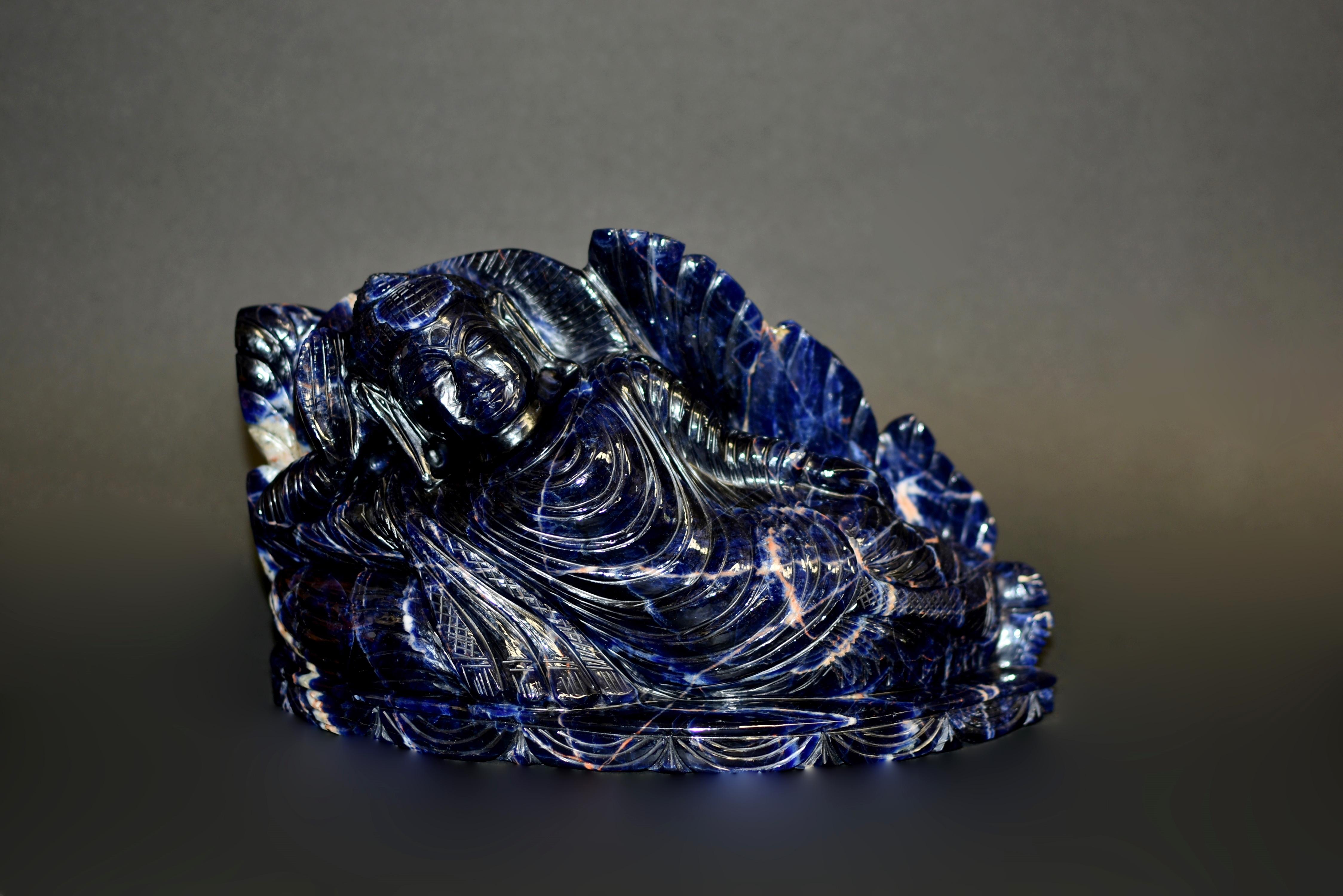 A rare, natural gemstone Sodalite reclining Buddha statue. Of the highest grade Sodalite, with saturated deep royal blue.  Carved lying on his right side with hand supporting the head, dressed in a long robe with rippling folds, the face with serene