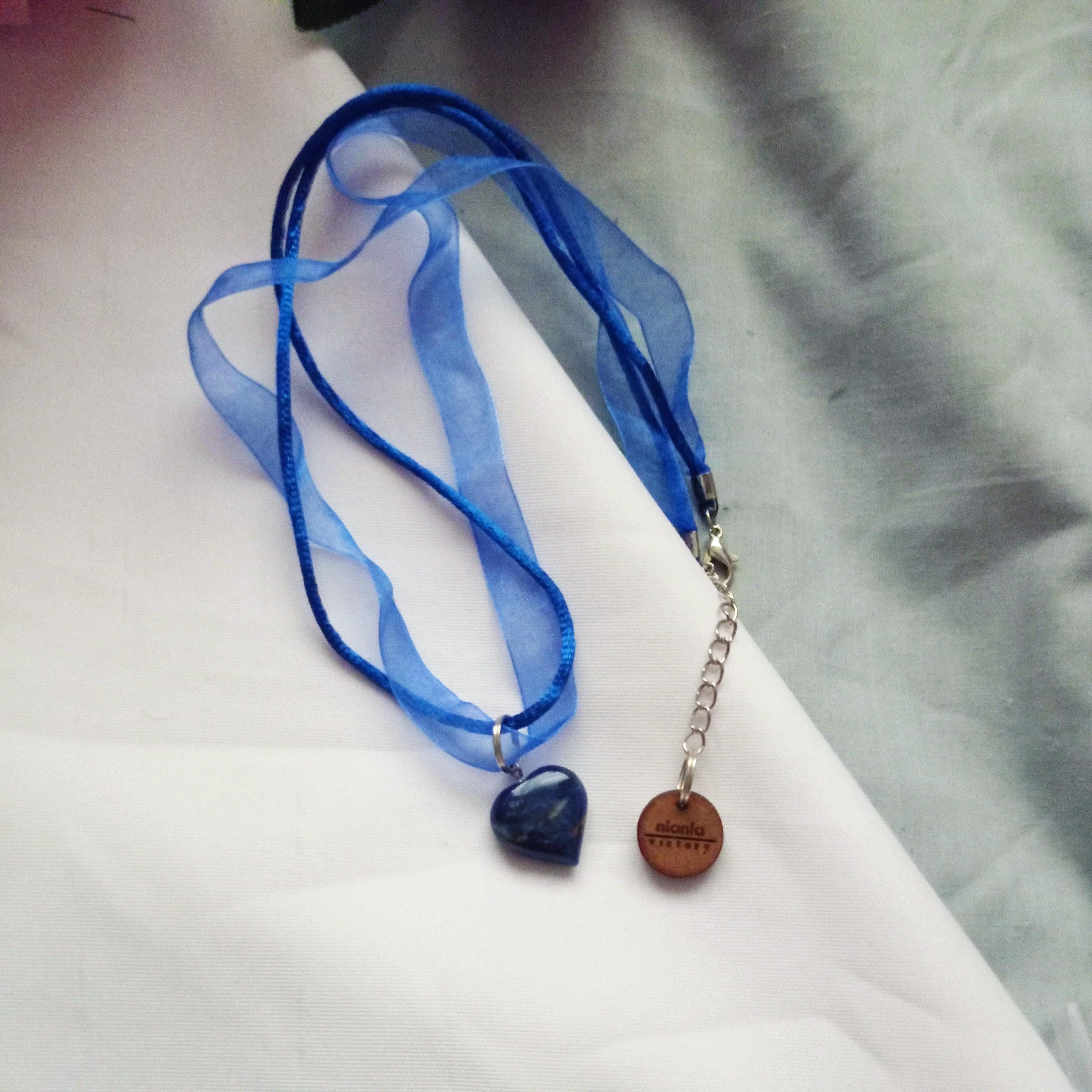 Picture a warm blue sky, with tropical birds in the air and fluffy white clouds, these are colours are all found in Sodalite. The depth of blue skies are presented in this beautiful Sodalite pendant. Matched to 20 inch royal blue organza & ribbon