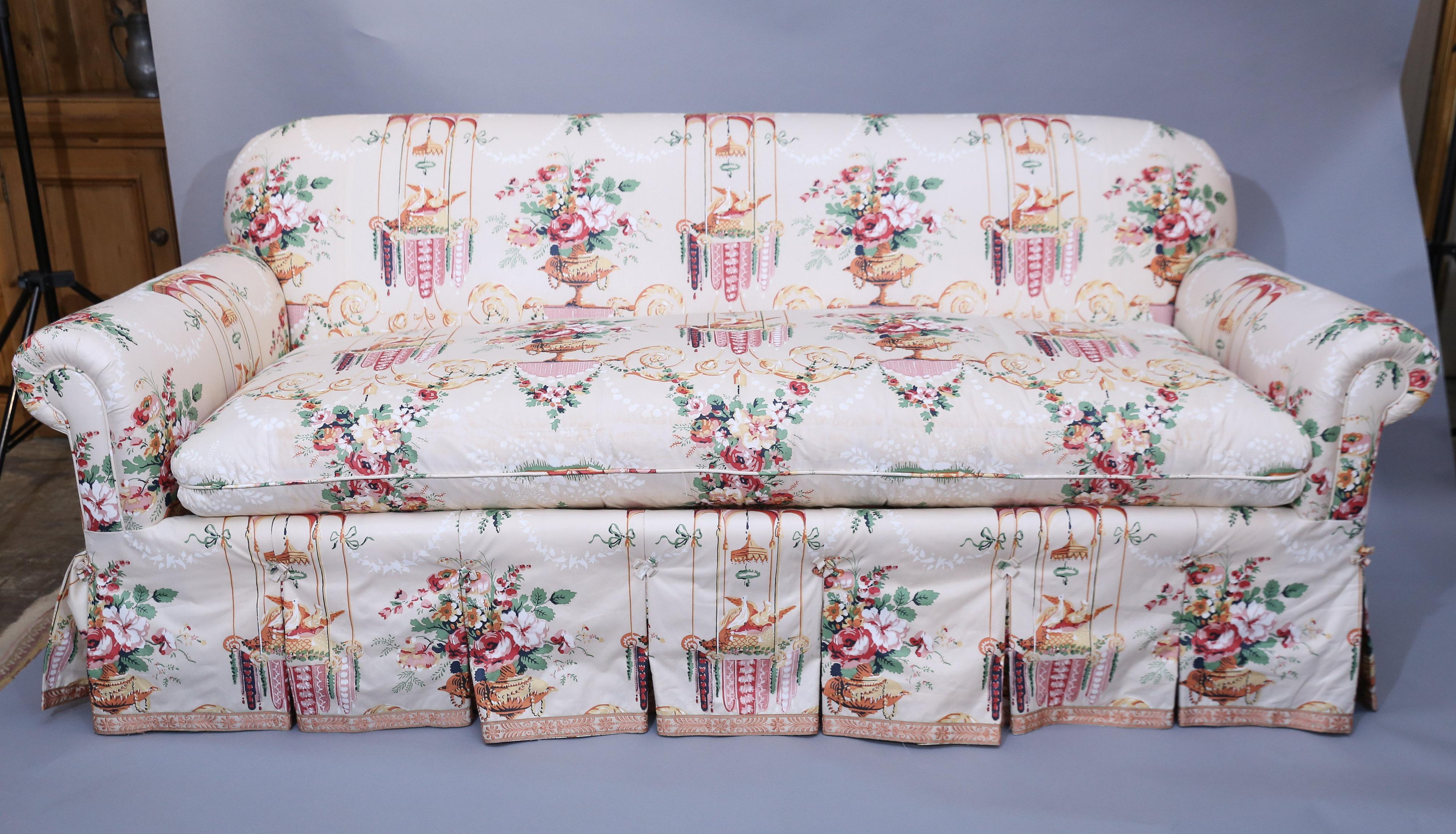 Roll arm, knife edge cushioned sofa is upholstered in a cotton floral print. Sofa upholstery is finely detailed with pleated back and sides and a deck skirt.
There are five assorted trimmed pillows.

Pair of Slipper chairs are in same fabric and are