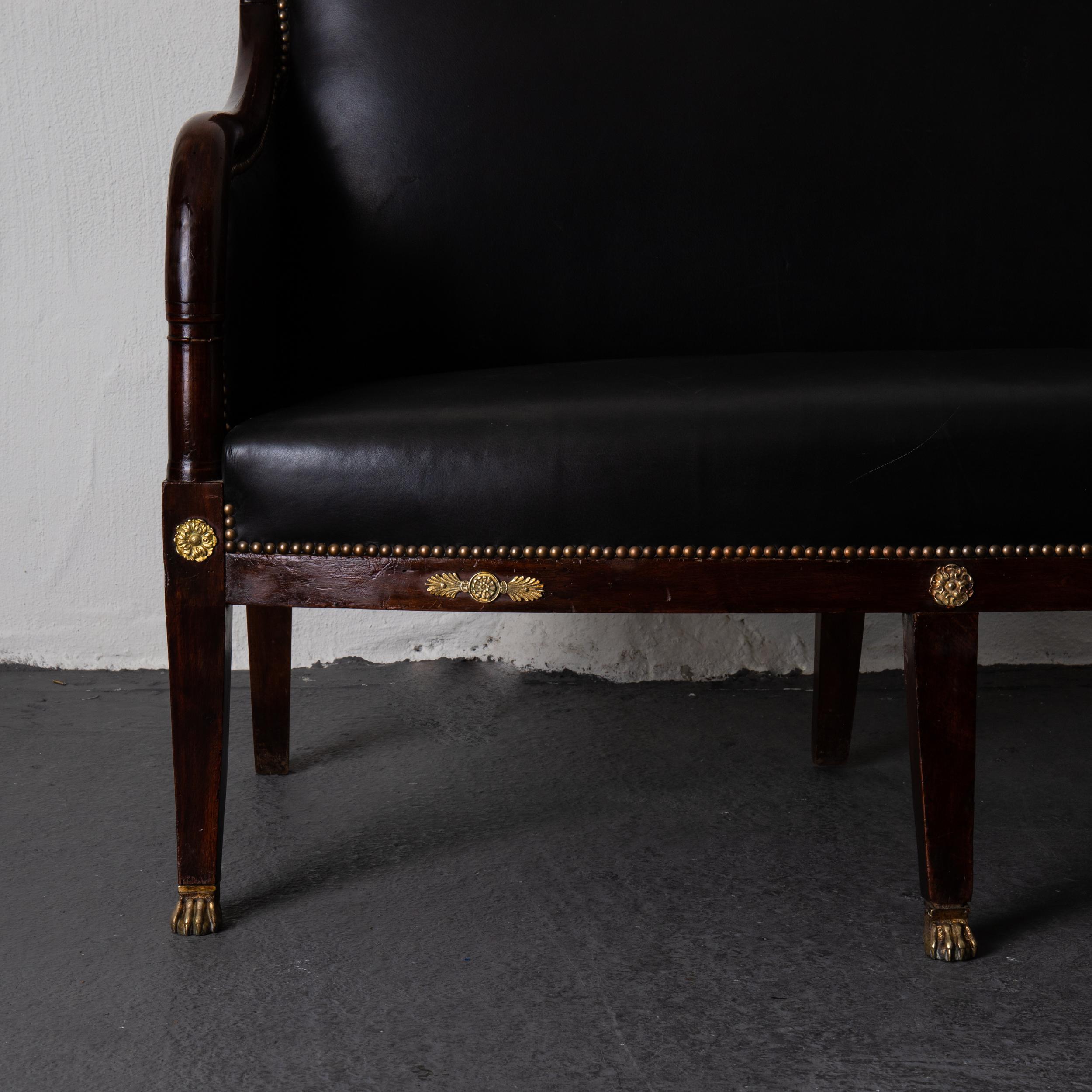 A rare sofa made in France during the Empire period, circa 1790-1810. Mahogany frame with gilded brass decor shaped as palm leaves. Tapered legs ending with lion feet casters. Upholstered in a black leather and antiqued brass nailheads.



 