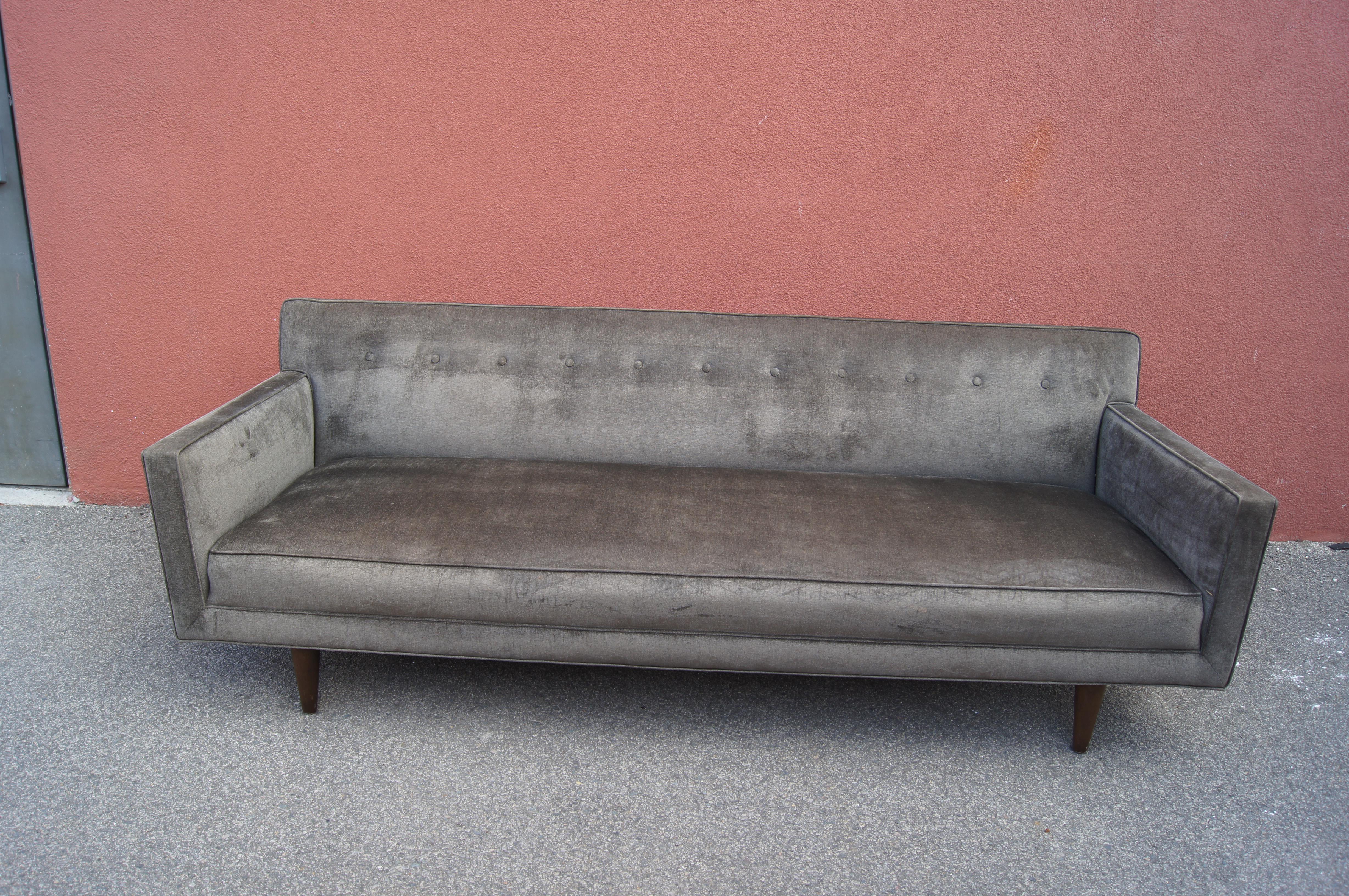 This elegant sofa is a classic 1950s design by Edward Wormley for Dunbar. It features a tufted back and a long bench seat resting on tapered walnut feet. The sofa has been reupholstered in Knoll's soft Haze textile in Mushroom.