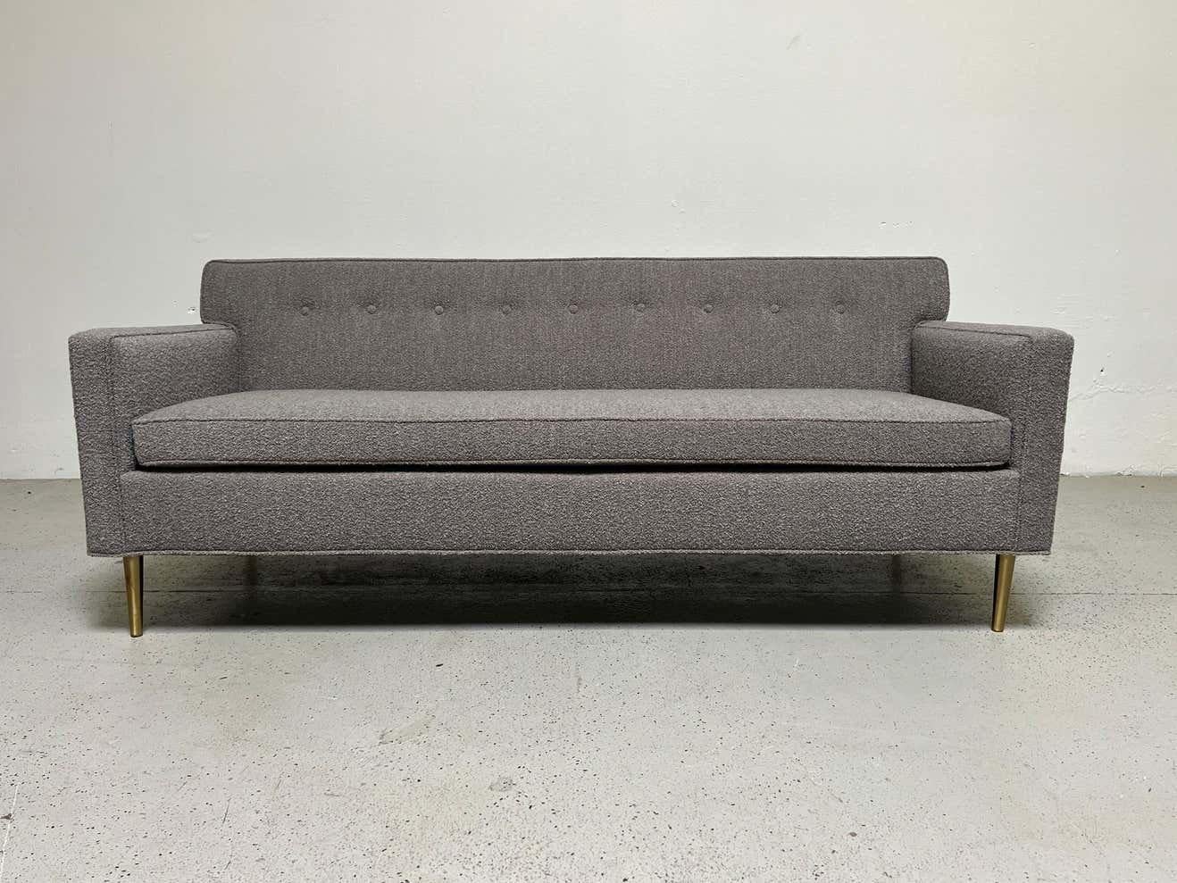 A small sofa / settee designed by Edward Wormley for Dunbar. Iconic form with tapered brass legs. Fully restored and upholstered in Designtex / Lambert / Smoke.
