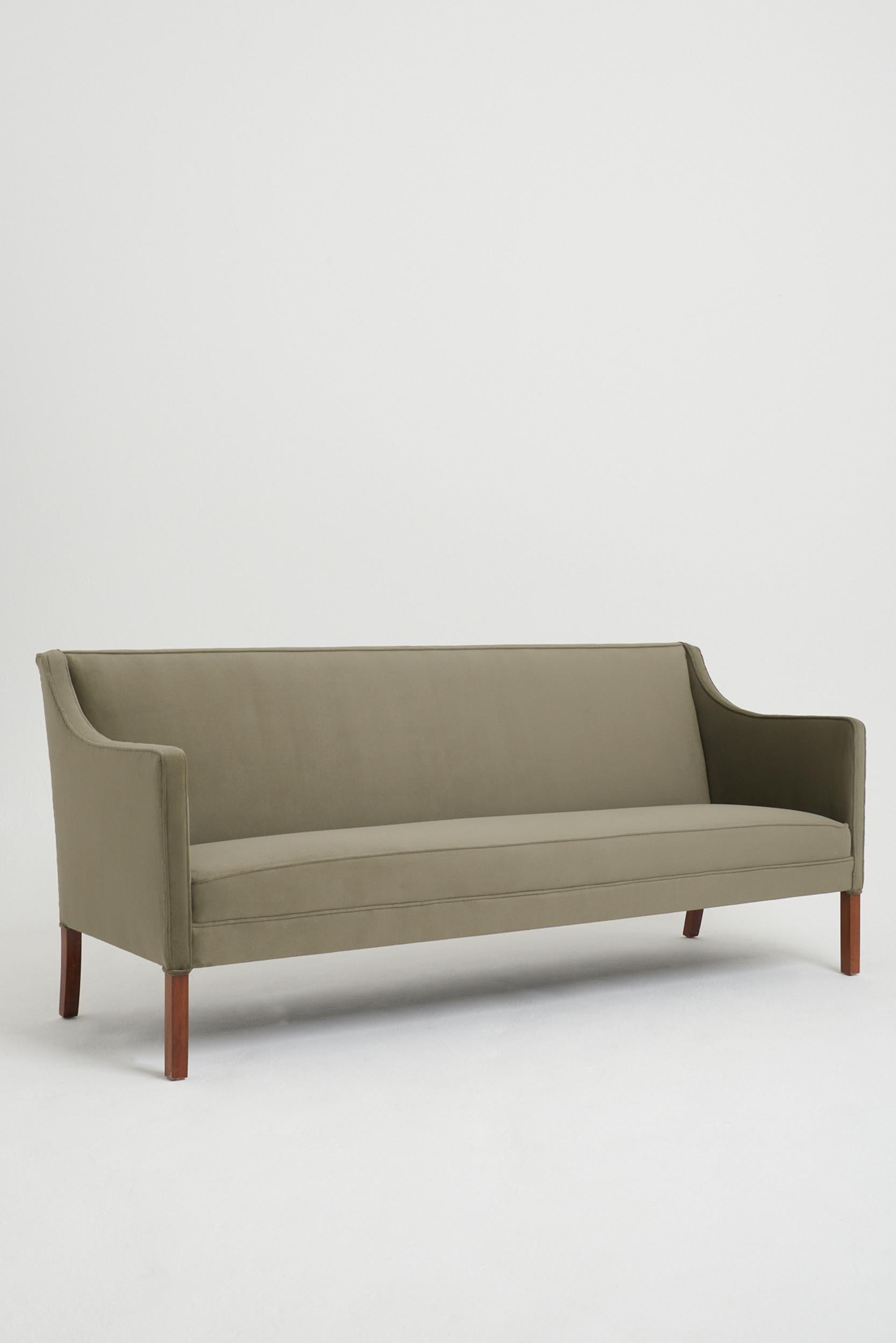 A mahogany sofa by Jacob Kjær (1896-1957).
Upholstered in Perennials velvet. 
Denmark, Circa 1940.
87 cm high by 203 cm wide by 70 cm depth, seat height 45 cm.