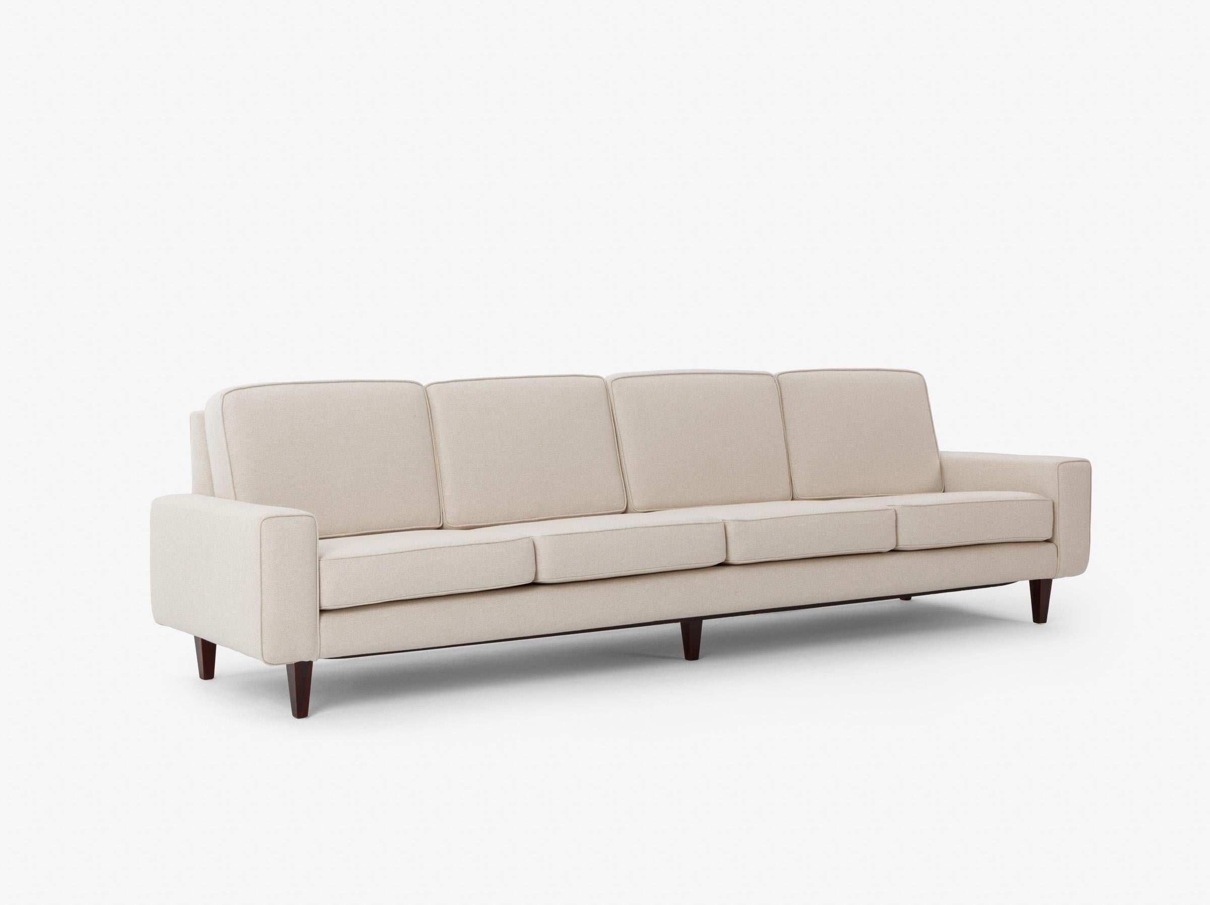 Cet élégant canapé quatre places illustre l'engagement de Joaquim Tenreiro en faveur de la légèreté, des proportions et d'une construction raffinée. Reposant sur un mince socle en bois de rose - une caractéristique de son vocabulaire - la pièce