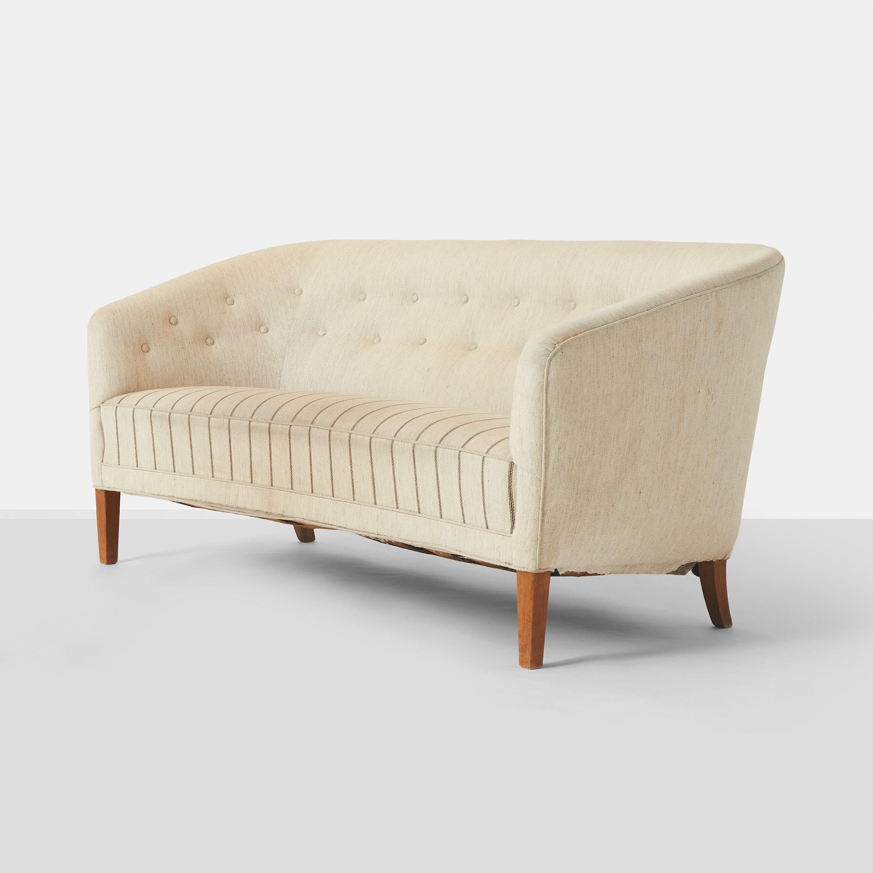 An elegant two seat sofa by Danish cabinetmaker Ludvig Pontoppidan. The sofa features curved edges and sloped arms, mahogany legs and upholstered seat, back and sides.