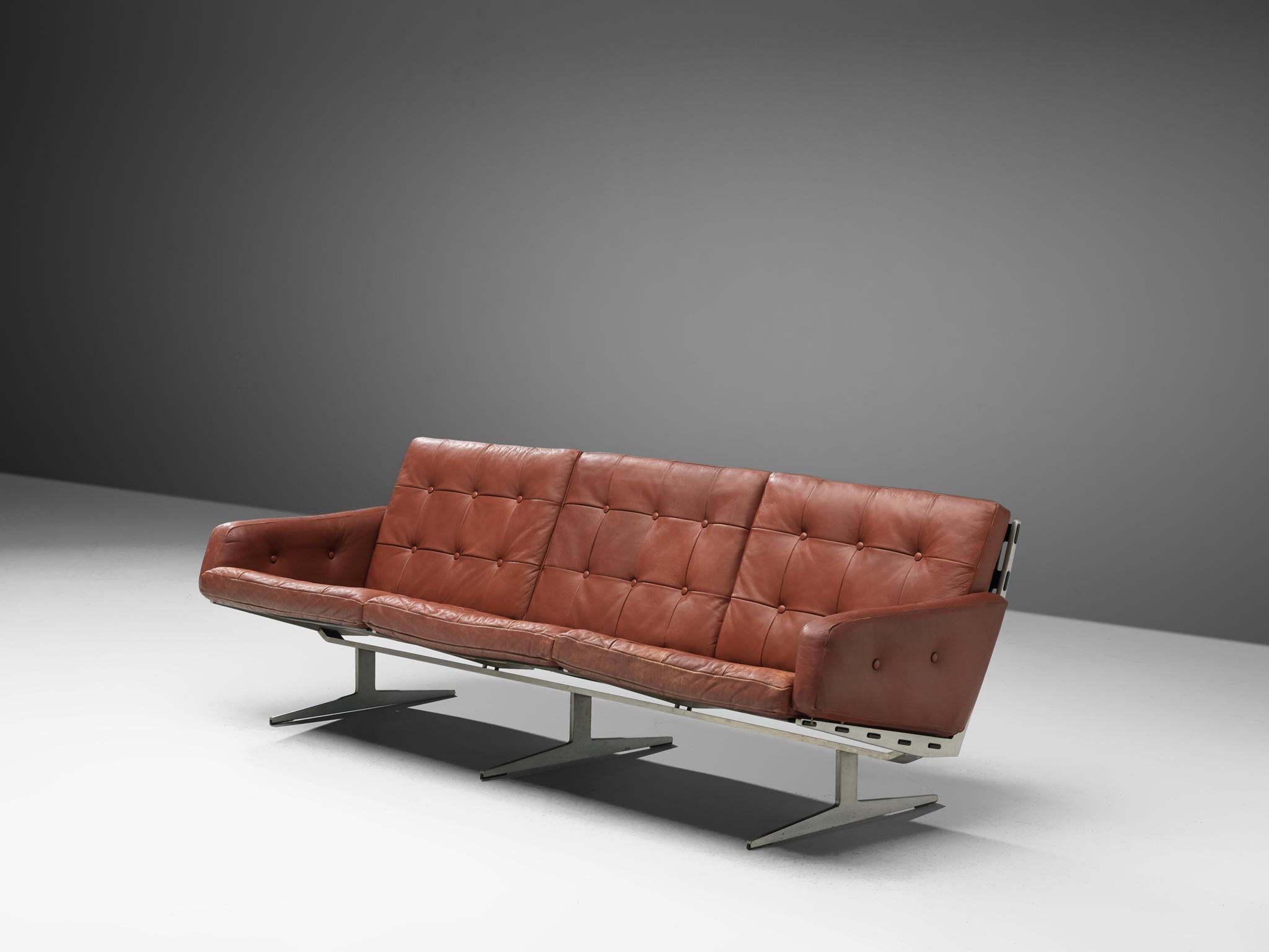 Sofa, steel and leather, Denmark, 1960s. 

This Danish sofa holds an L-shaped seating and this shape is repeated in the legs. A double L is mirrored to form the steel 'slipper.' The base of this sofa is characteristic and provides an open character