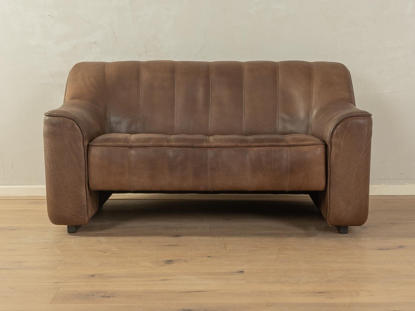 Sofá clásico DS-44 de los años 70 de De Sede con la llamativa funda original de cuero de búfalo marrón con una bonita pátina y costuras gruesas. El asiento del biplaza se puede extraer fácilmente para que resulte más acogedor y