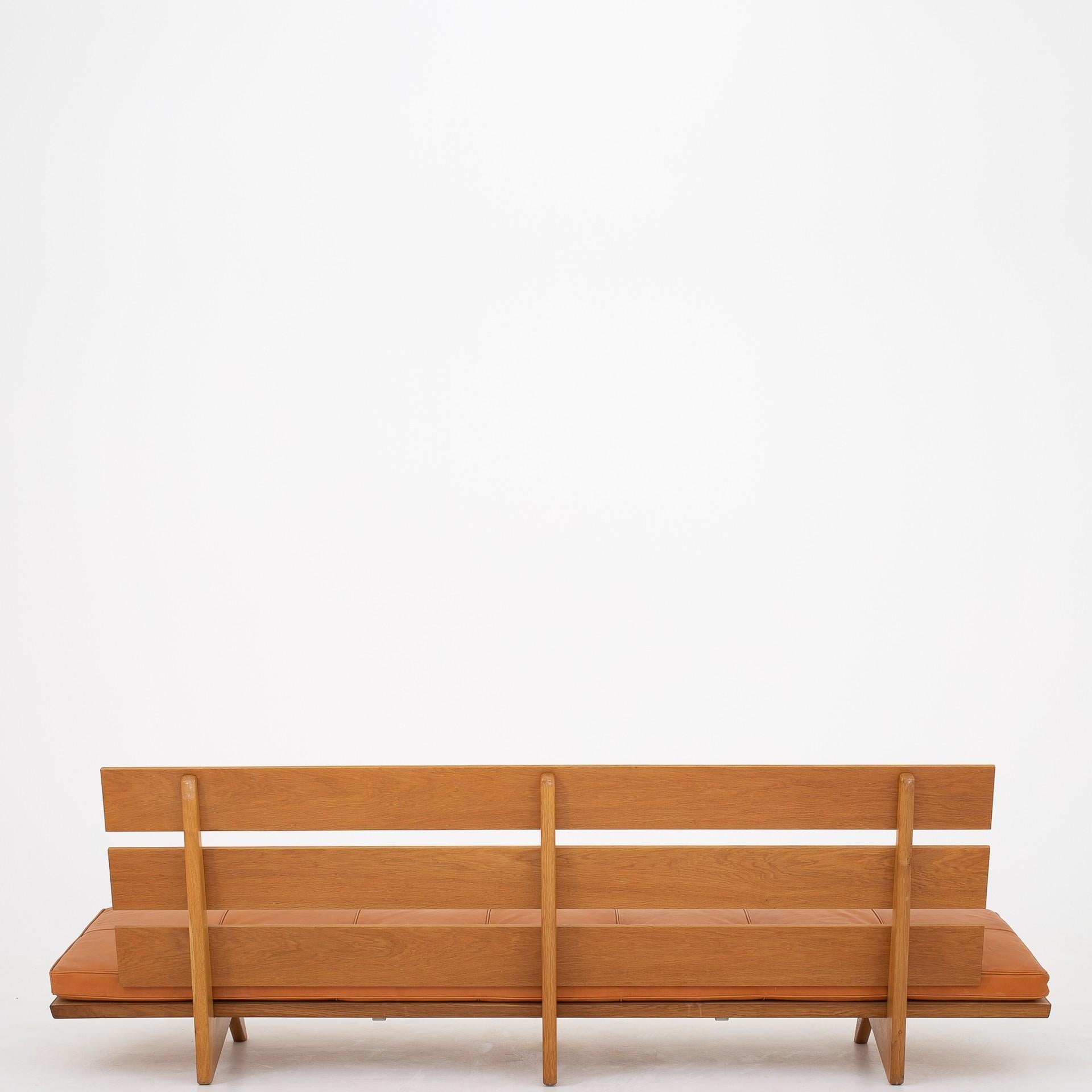 Sofa in patinated oak with cognac leather cushion.