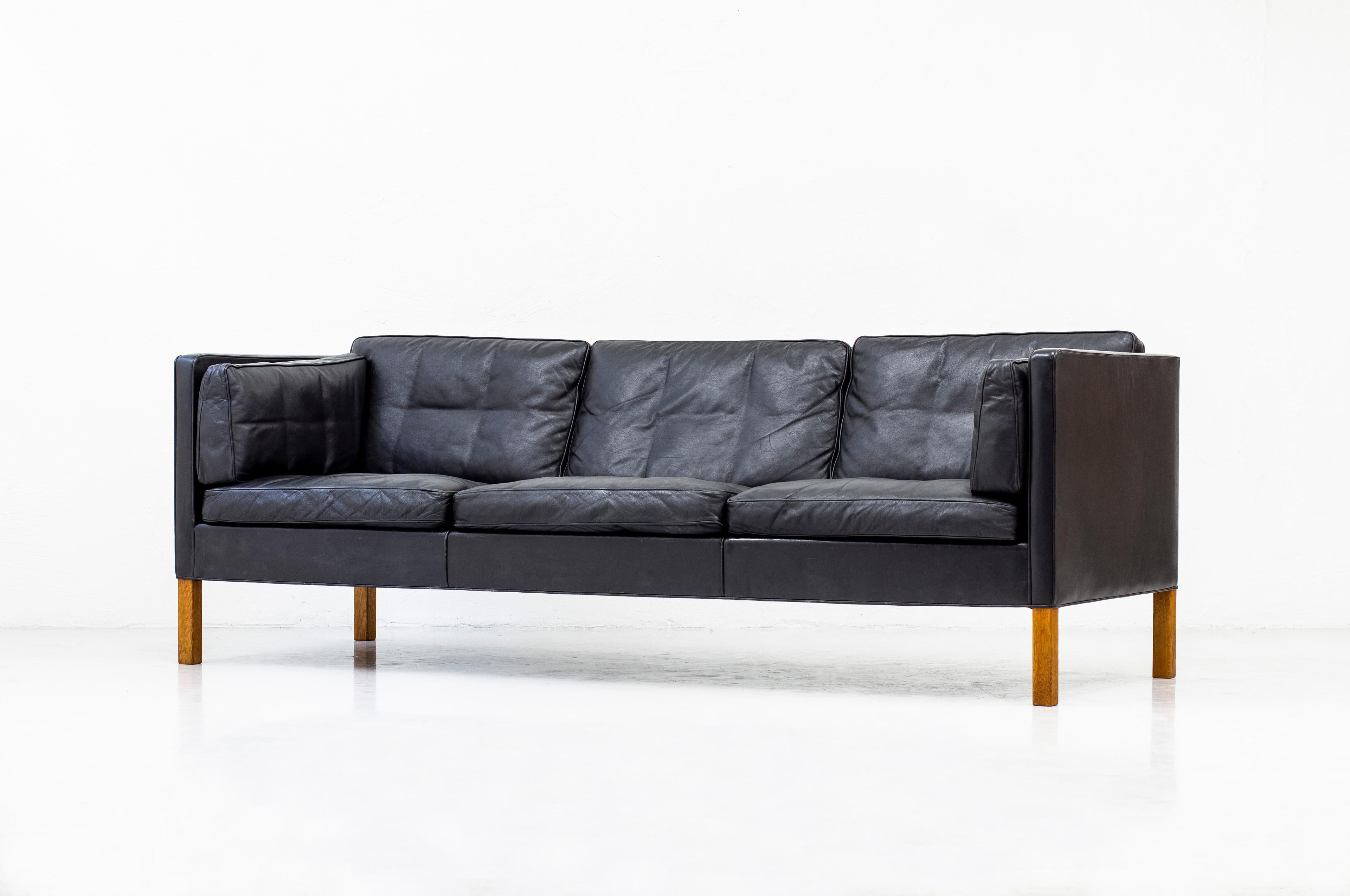 Sofa model 2443 designed by Børge Mogensen. Designed in 1975 and produced by Fredericia Furniture in Denmark. This example ca late 1970s. Black original leather and solid oak legs. Down feather filled cushions. Very good vintage condition with age