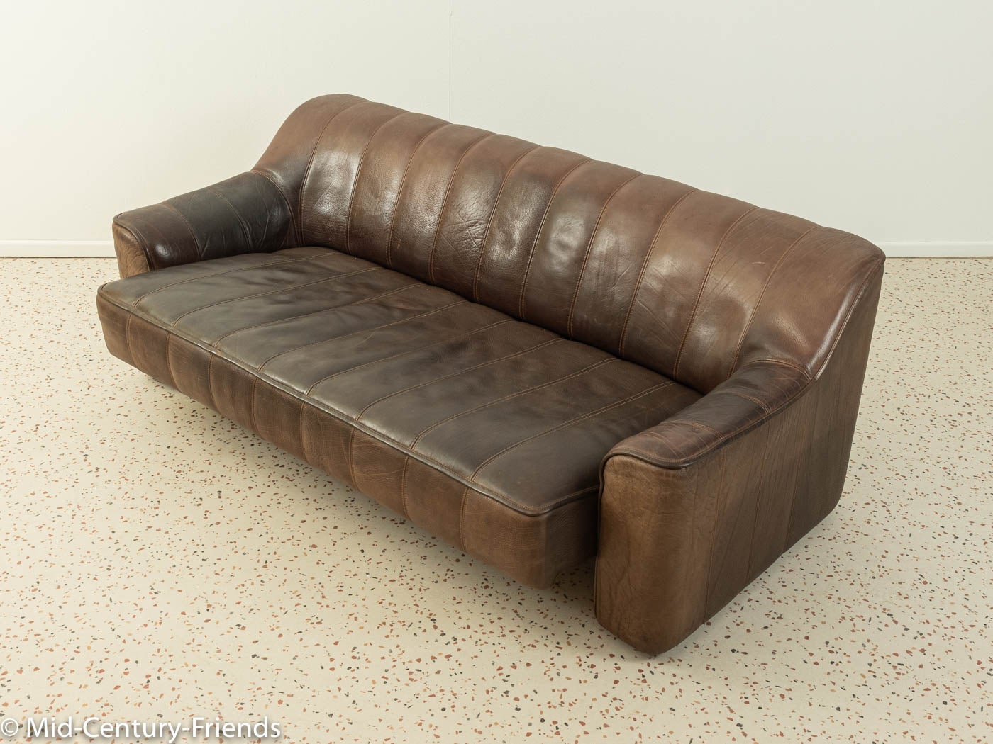 Classic sofa from the 1970s. Model DS-44 by DeSede with the striking original cover made of brown buffalo leather and coarse stitching. The seat squab of the three-seater can be enlarged with a simple movement and will transform into a more cozy and