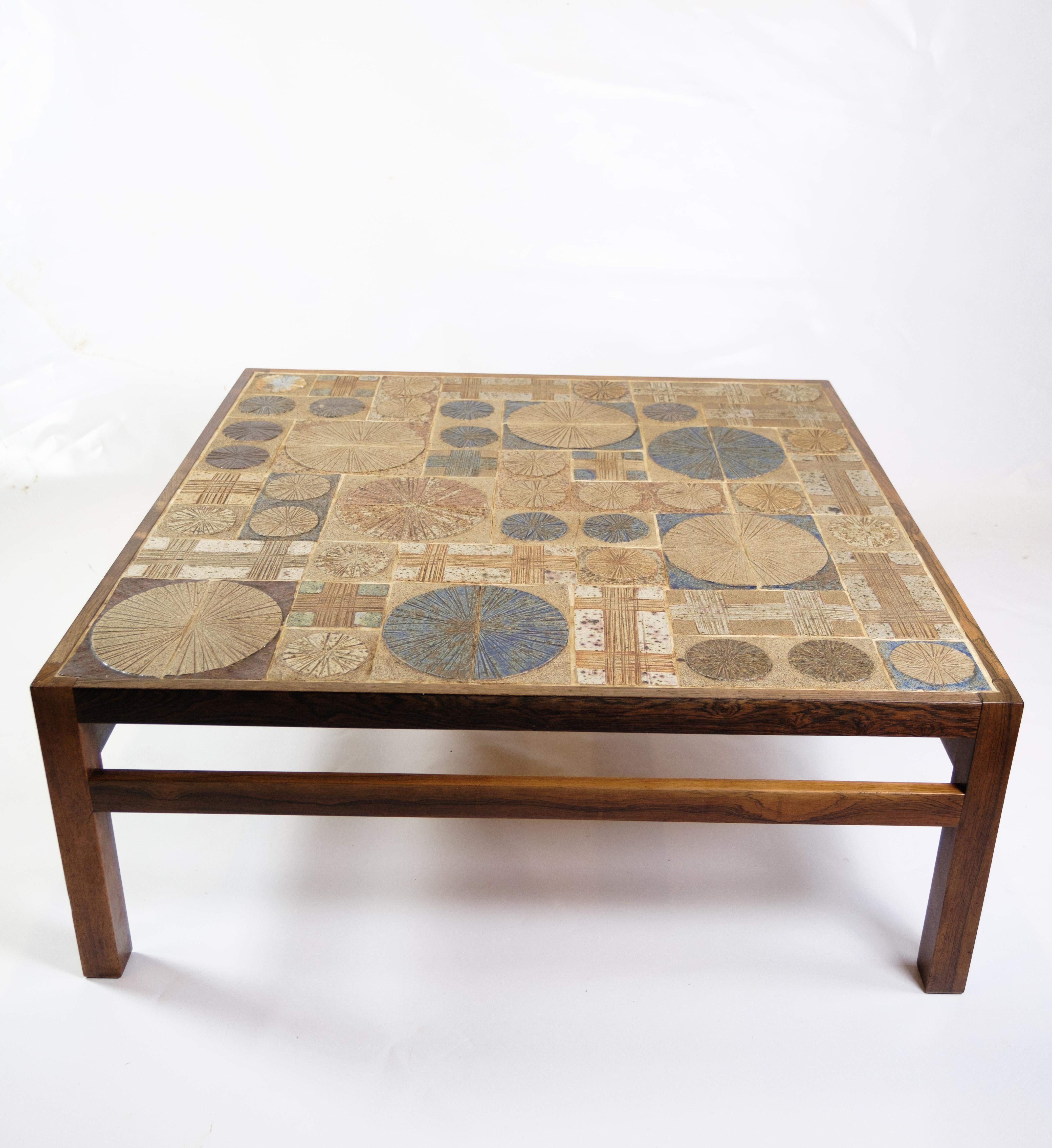 La table basse, faite de bois de rose et de céramique, est une pièce unique conçue par Tue Poulsen et produite par Haslev Møbelsnedkeri en 1960. Cette table basse se distingue par sa combinaison de matériaux et de détails artisanaux qui reflètent le