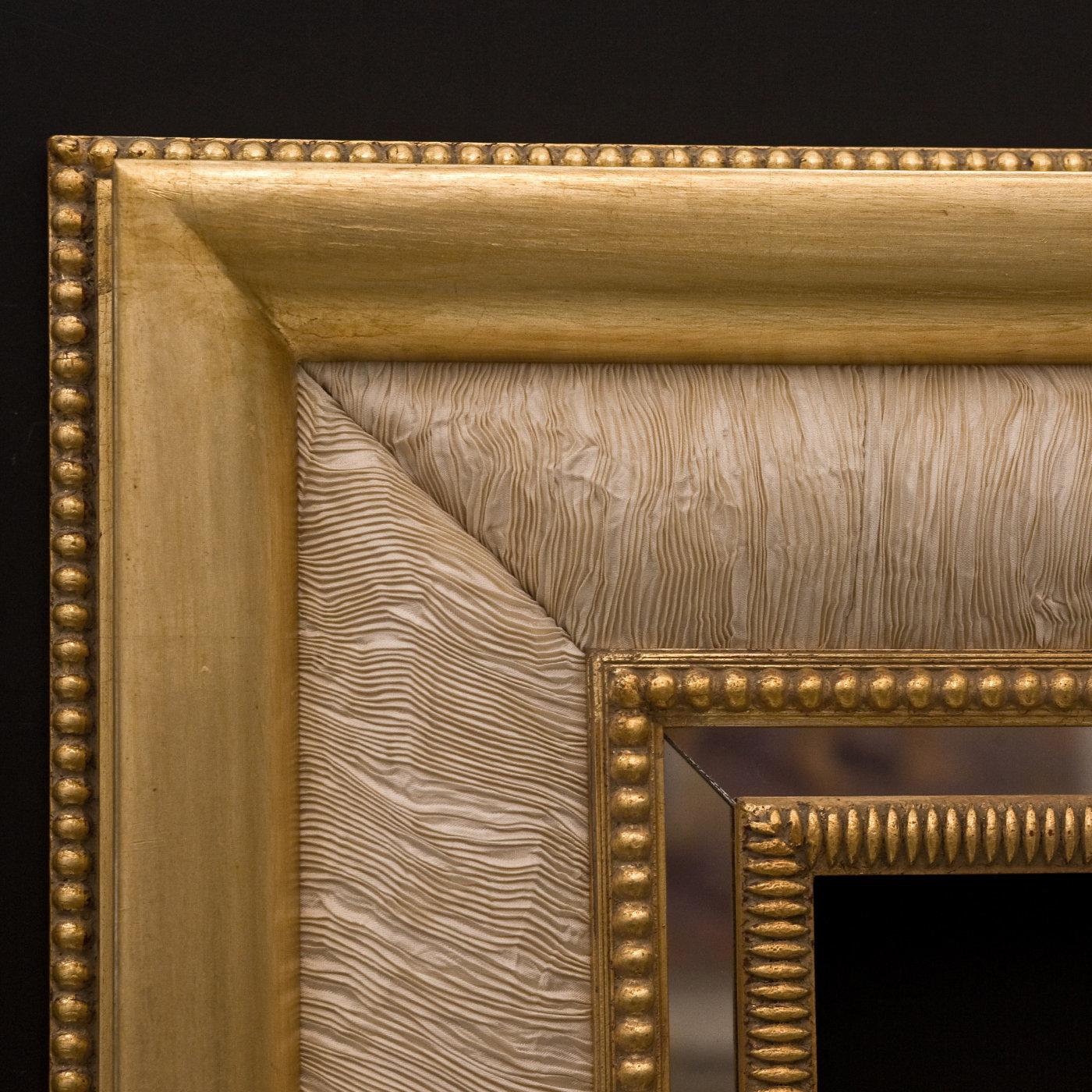 A singular design to enrich an eclectic contemporary interior, this exquisite frame will ideally enclose a fine and luminous mirror. Handcrafted of wood, its rectangular shape is enriched with gold leaf, ivory silk inserts, and smokey mirror