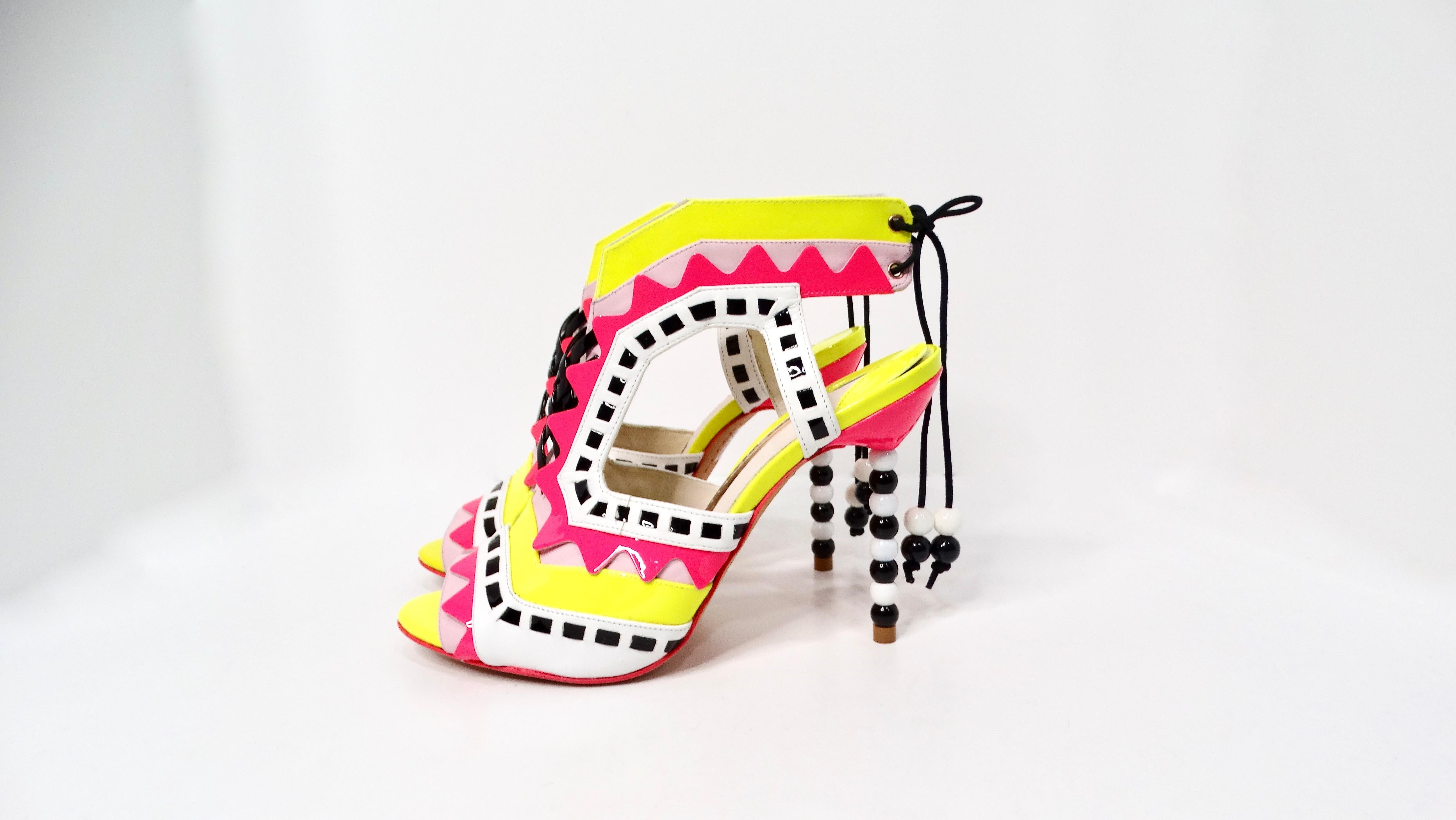 Entrez dans l'été avec la sophistication enjouée des sandales à lanières en T imprimées en cuir verni multicolore de Sophia Webster. Ces talons vibrants présentent un mélange étonnant de teintes néon roses et jaunes complétées par des détails blancs