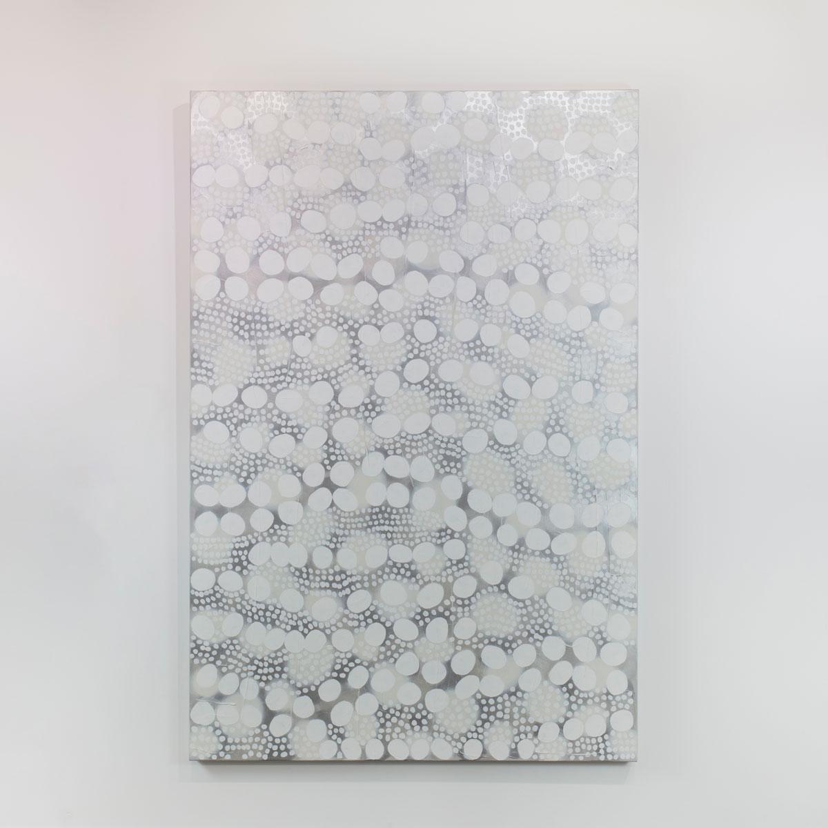 This large abstract statement painting by Sofie Swann features a white and light grey palette, with varying sizes of imperfect white circular shapes arranged with subtle metallic silver accents throughout the canvas. This painting is made on gallery