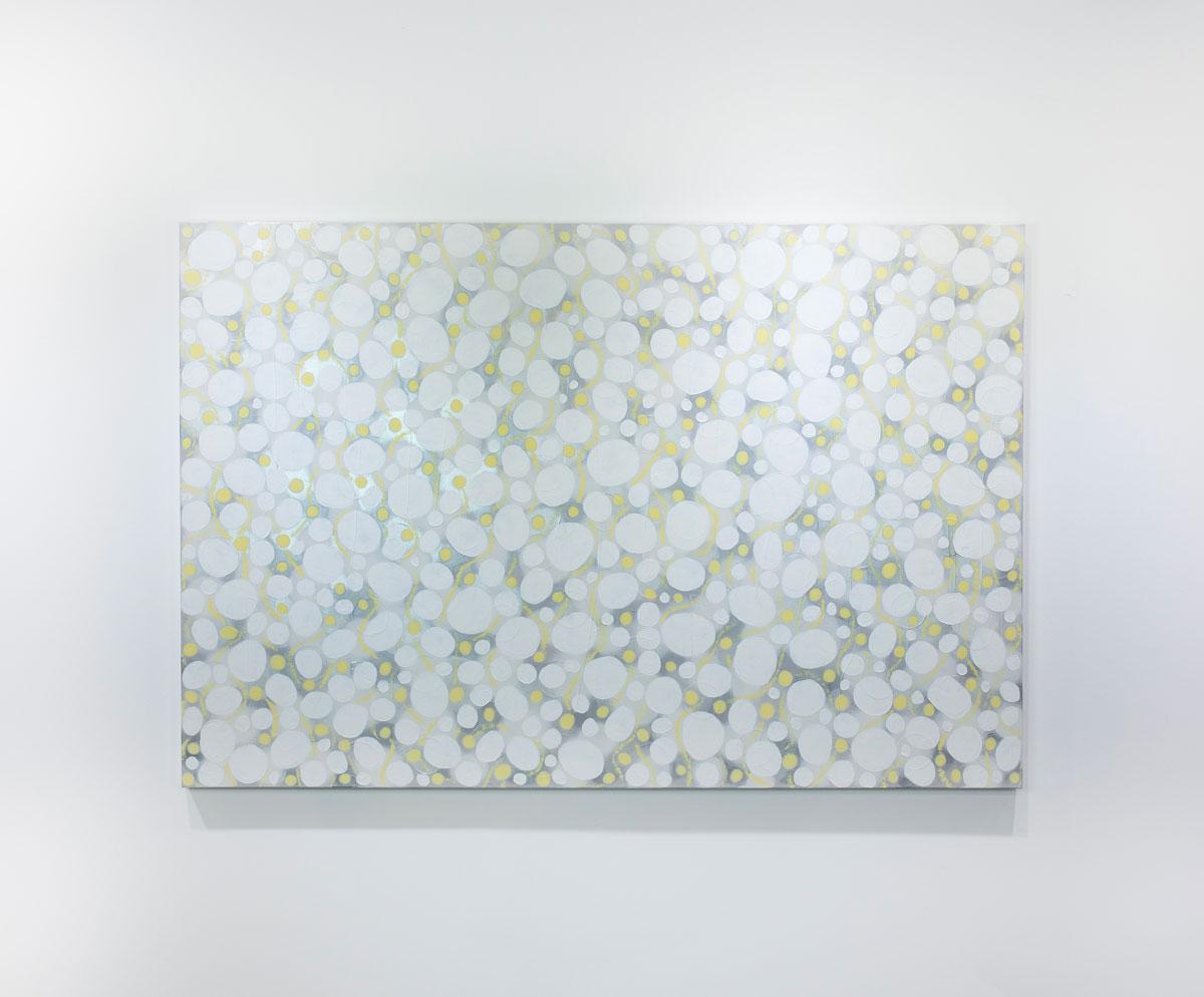 This large abstract horizontal statement painting by Sofie Swann features a light palette, with large white and small yellow circular shapes layered over a hazy grey and subtle silver metallic background. This painting is made on gallery wrapped