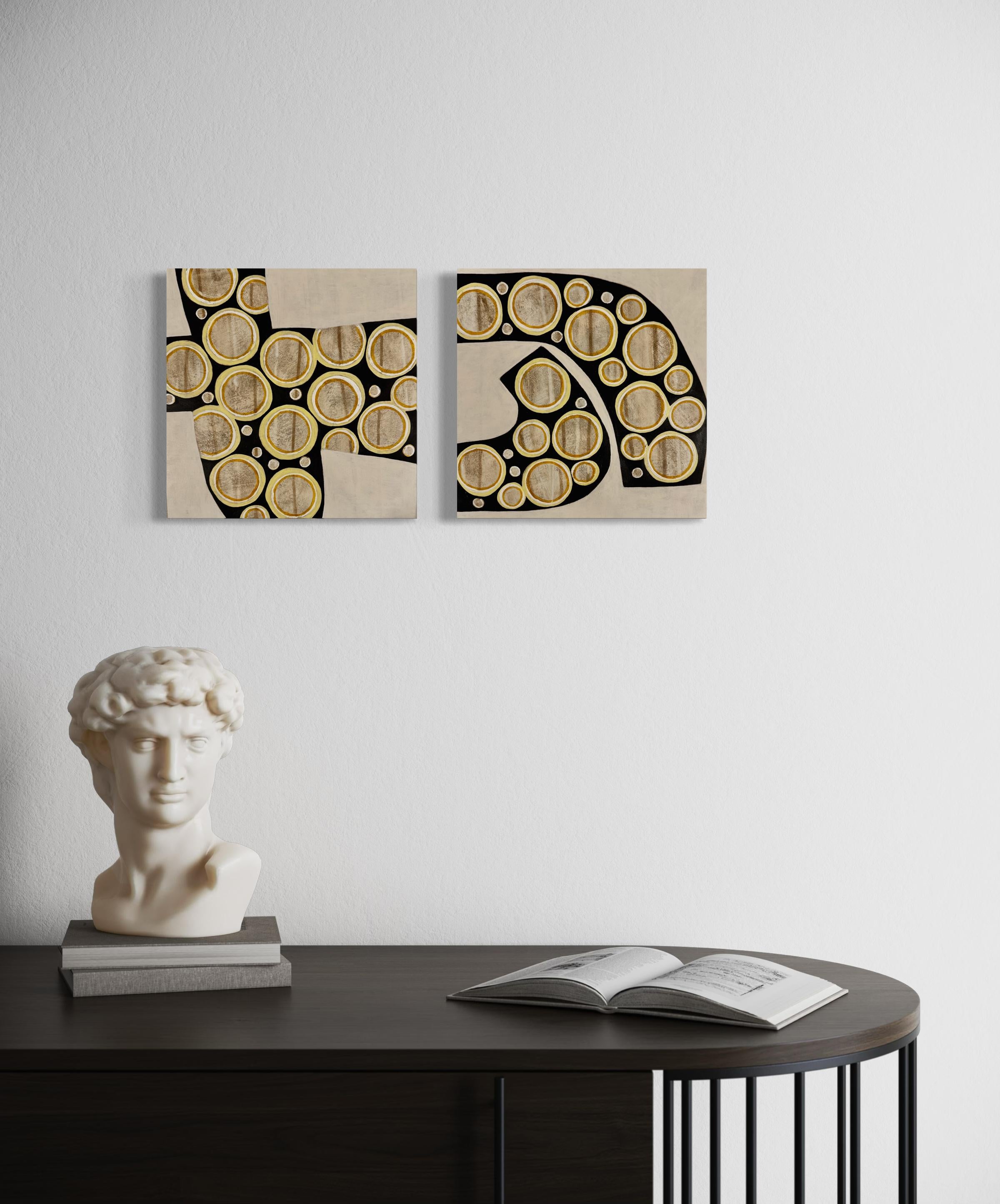 This abstract diptych (set of two paintings) by Sofie Swann features a warm neutral palette, with light brown circular shapes layered in black organic encompassing shapes, over a beige background. Both paintings are made with acrylic paint and