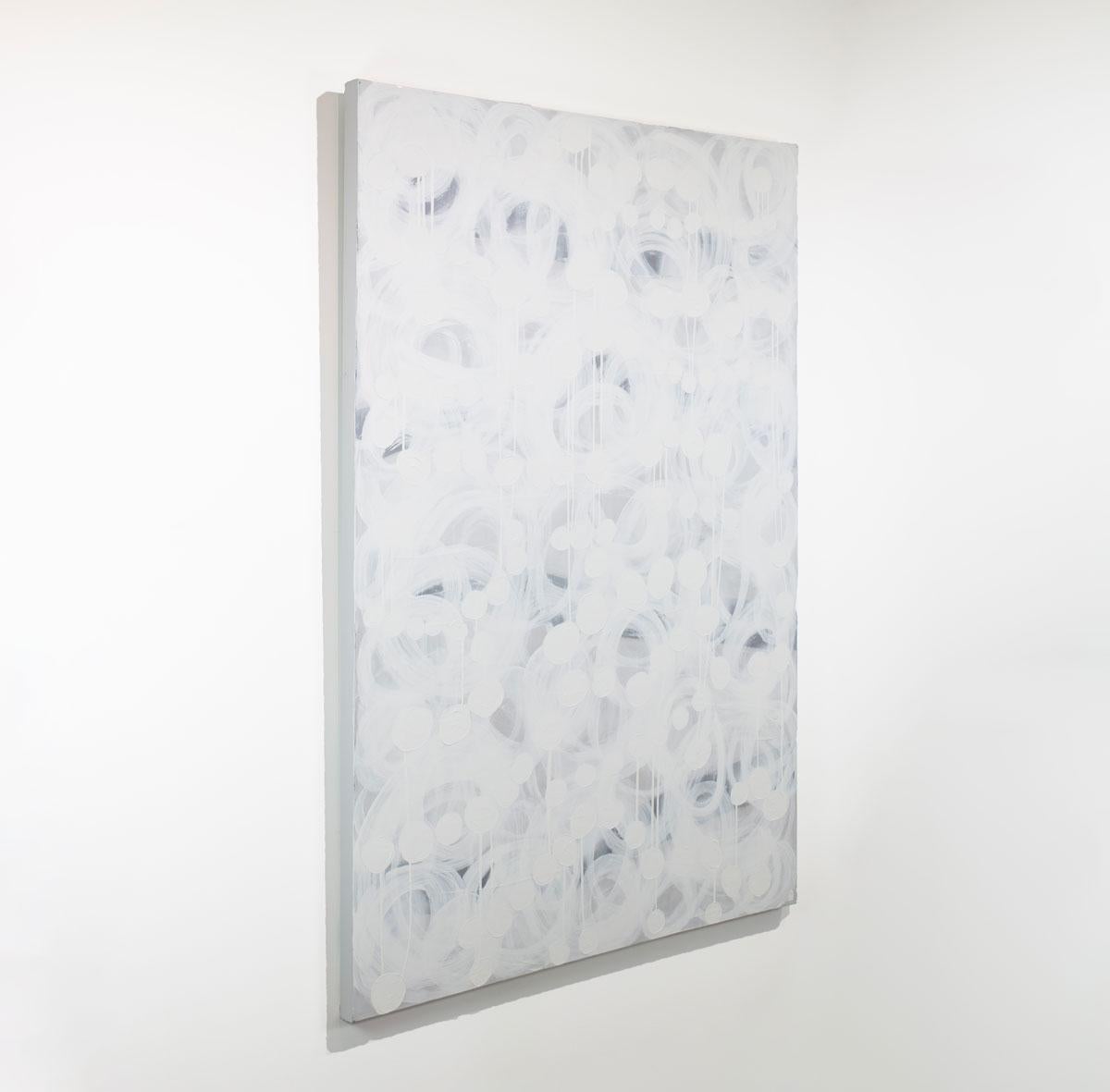 Ce grand tableau abstrait de Sofie Swann présente une palette de blanc et de gris clair, avec des coups de pinceau lâches qui forment des cercles concentriques énergiques sur toute la toile, superposés à de plus petits cercles blancs. Cette peinture