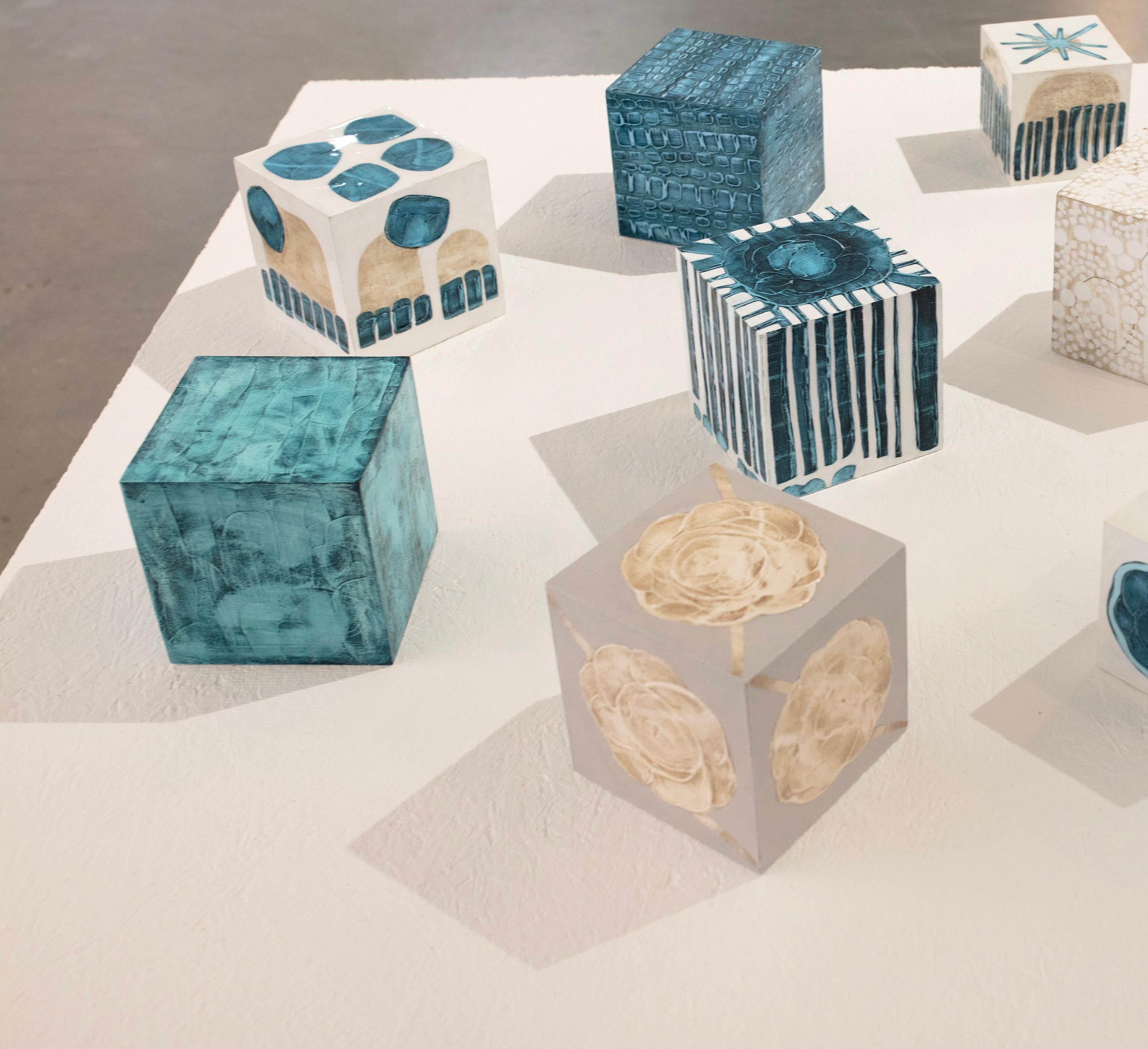 Ce cube sculptural de 5 pouces peint à la main par Sofie Swann est réalisé avec de la peinture acrylique et du gesso sur bois. Il présente une palette de sarcelles profondes avec une texture légère sur la surface du cube. Il est signé par l'artiste