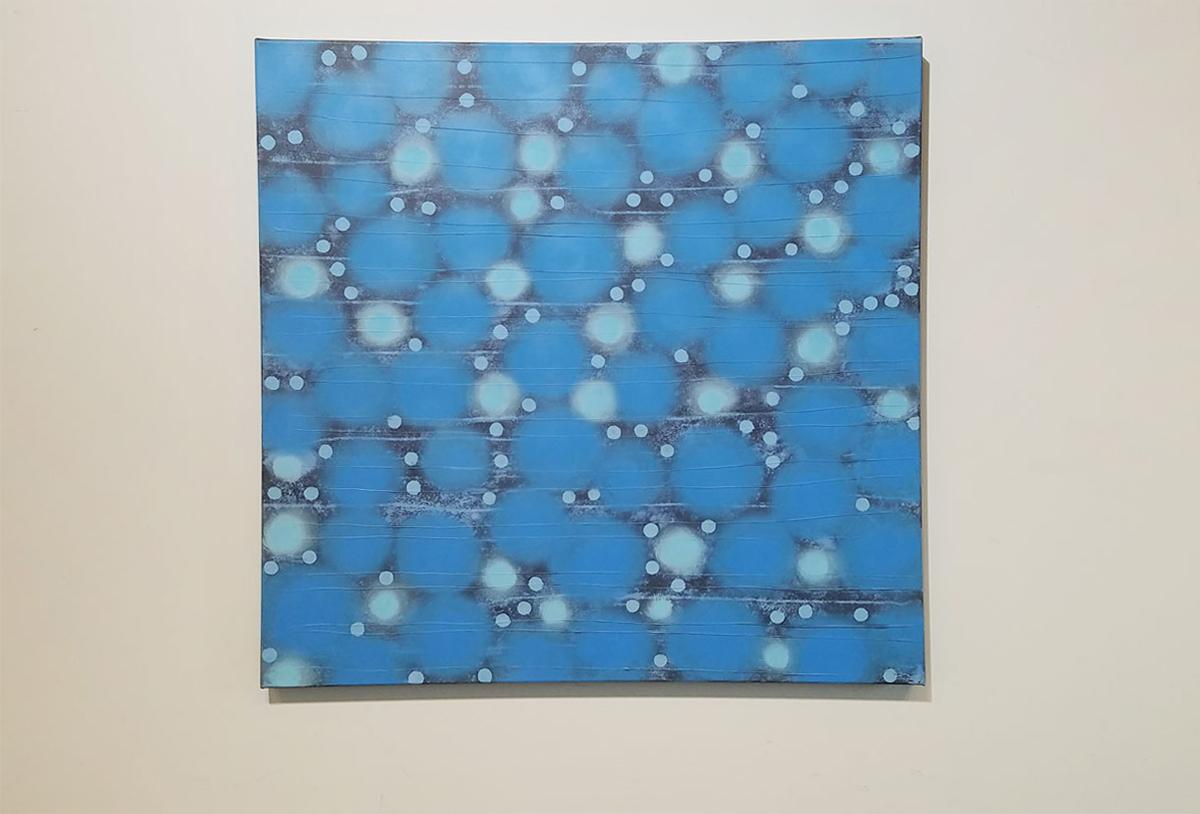 Cette peinture contemporaine fantaisiste présente des cercles bleu vif et sarcelle clair de tailles différentes, regroupés sur un fond noir. Les cercles n'ont pas d'arêtes franches, comme l'artiste a tendance à rendre ses formes géométriques et
