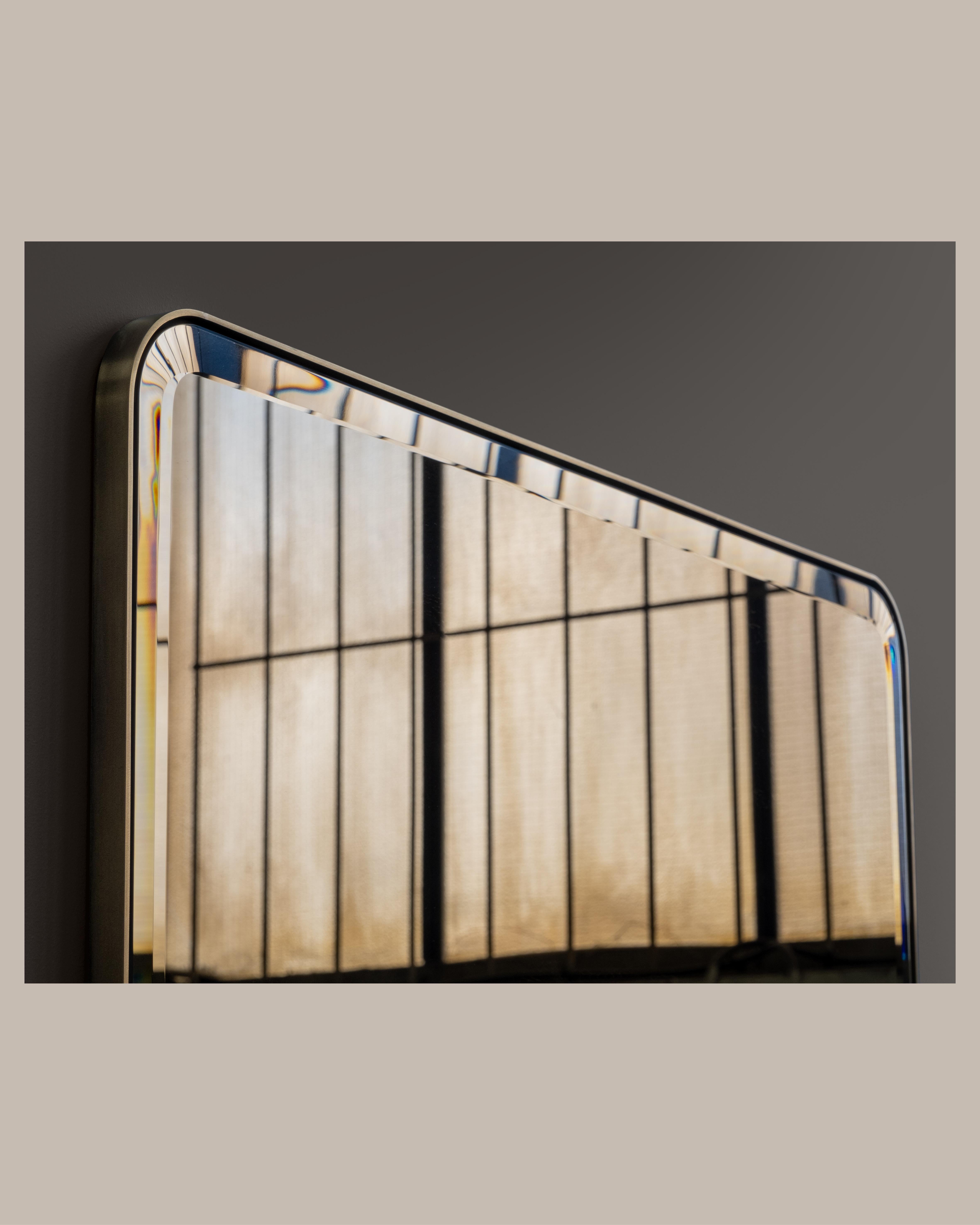 A wall mirror with bevelled glass mirror. Various metal, finish and mirror tint options are available. Hand crafted in the North to order.

Initial image shows a polished brass frame with bronze tinted mirror.