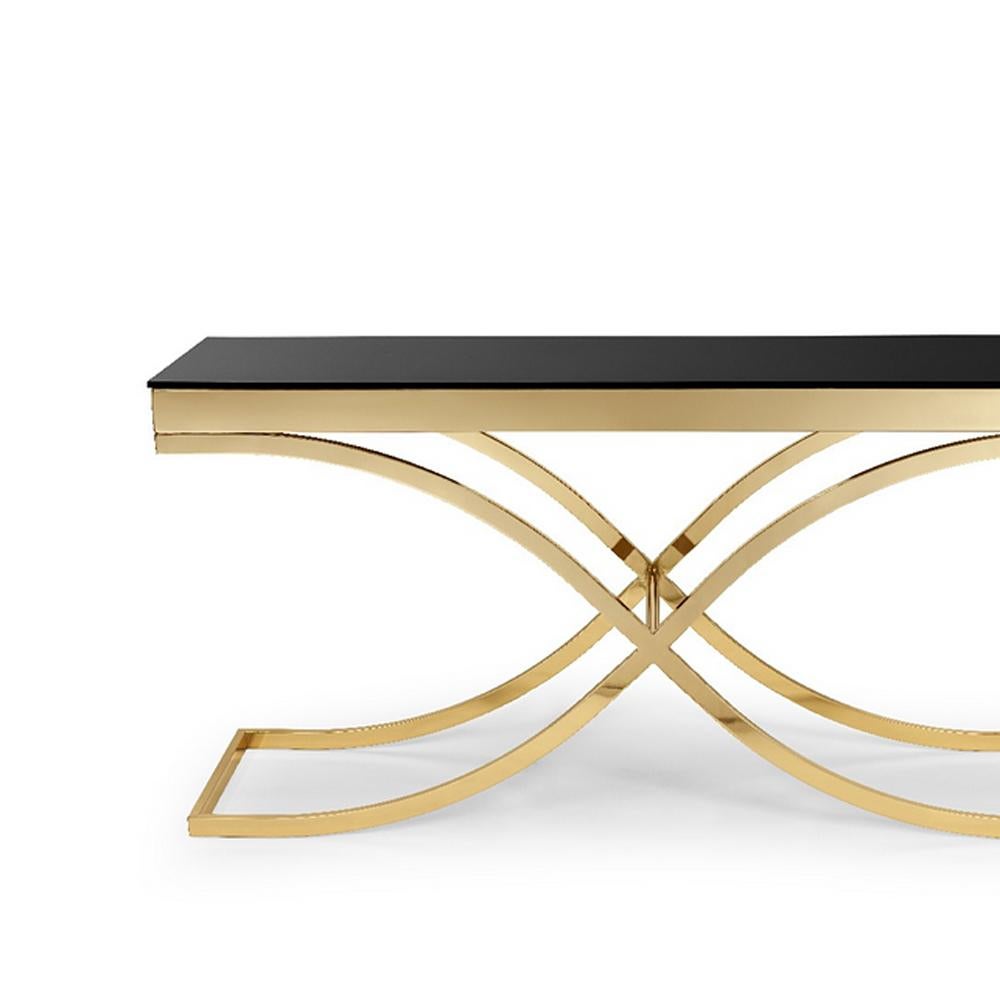Mesa consola soft cross con estructura en metal
en acabado dorado y con tapa de cristal negro templado.
También disponible en acabado cromado.