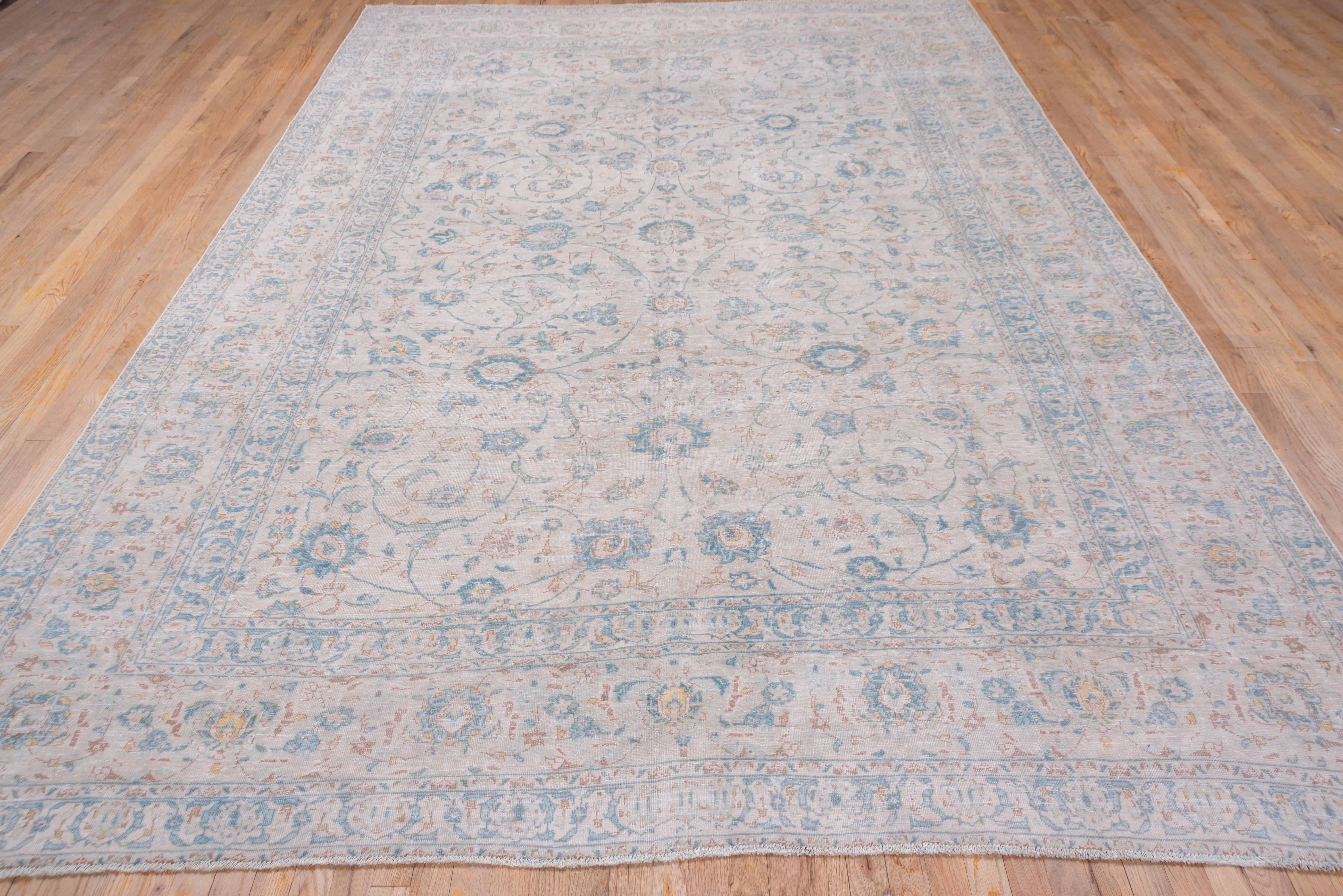 In a light cream and blue-grey/teal tonality, this NW Persian city carpet features a slender spiraling vine pattern with palmette anchors, within a tonally en suite border system including a spacious palmette and vine major frame. The field